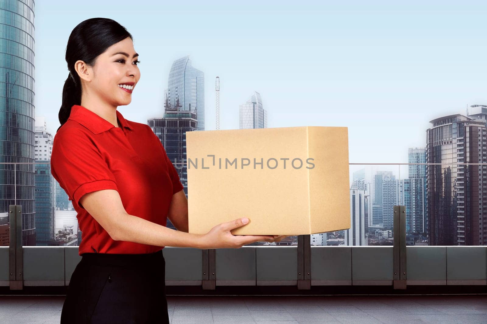 Young asian delivery woman carrying the package on the modern building
