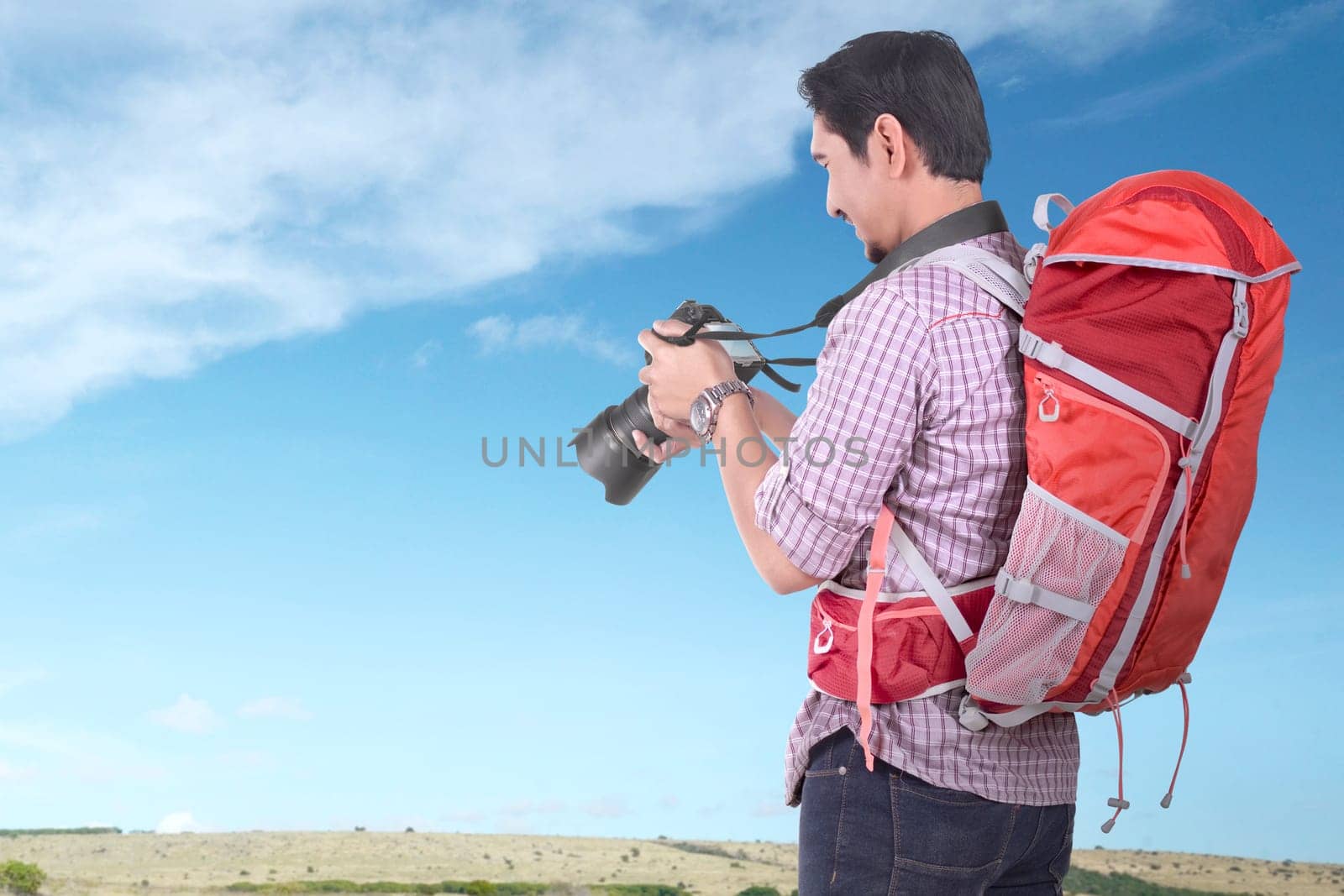Handsome asian tourist with backpack holding camera with blue sky background