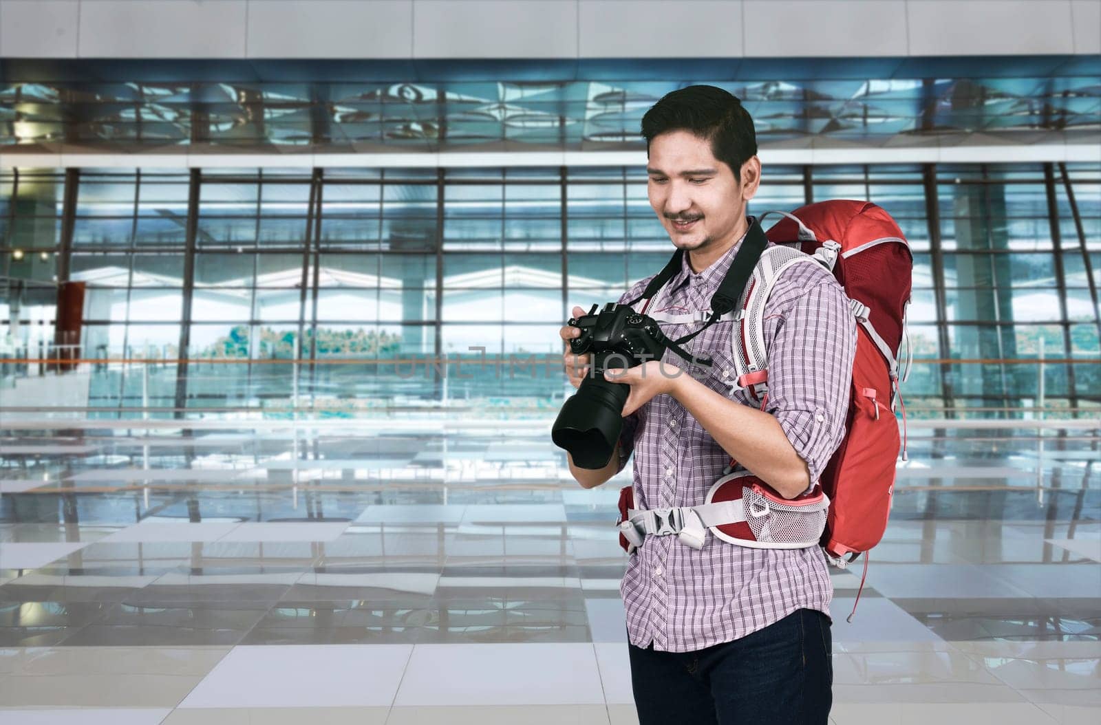 Handsome asian tourist with camera and backpack on the airport