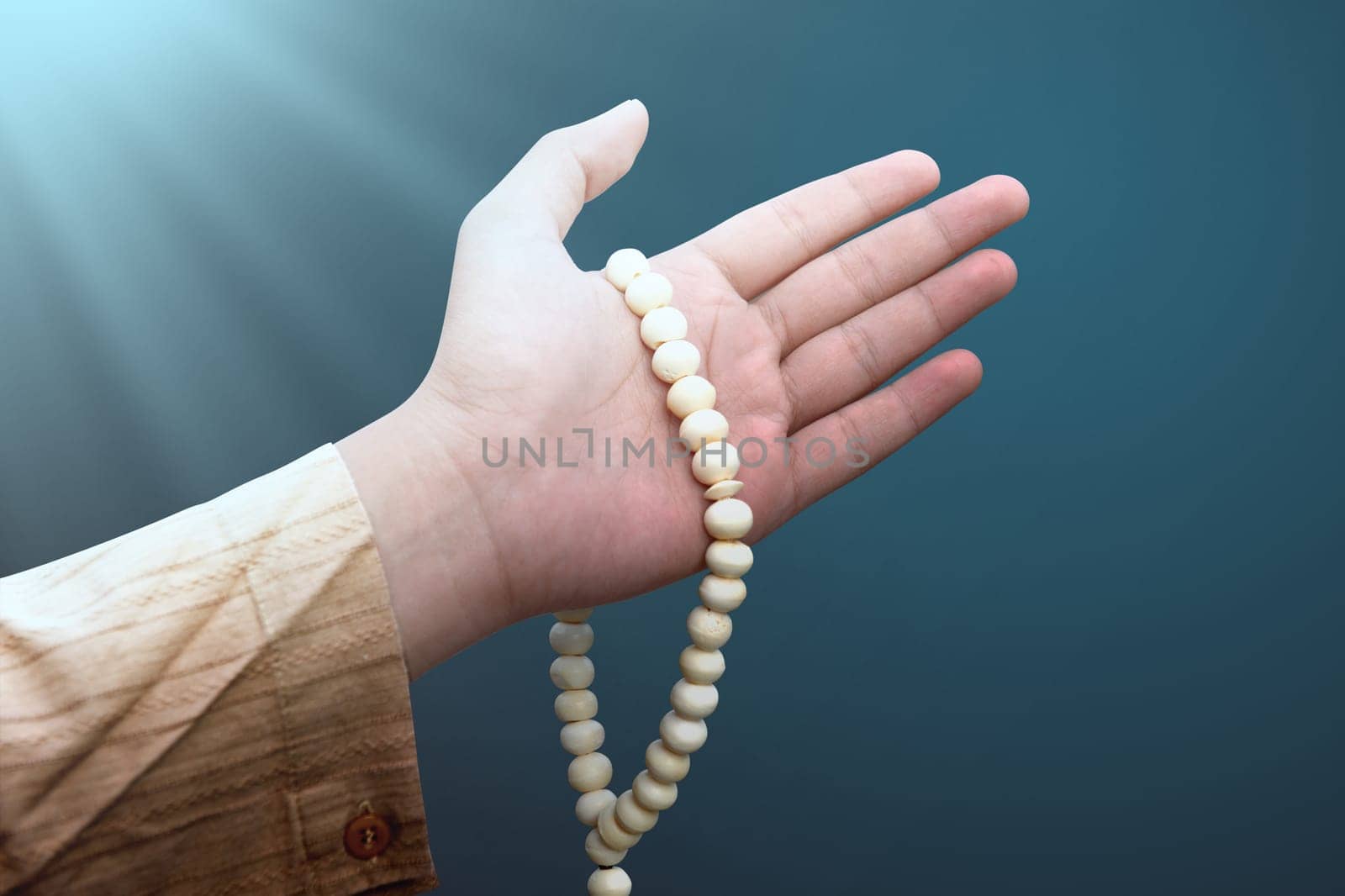 Muslim man holding prayer beads over bright background