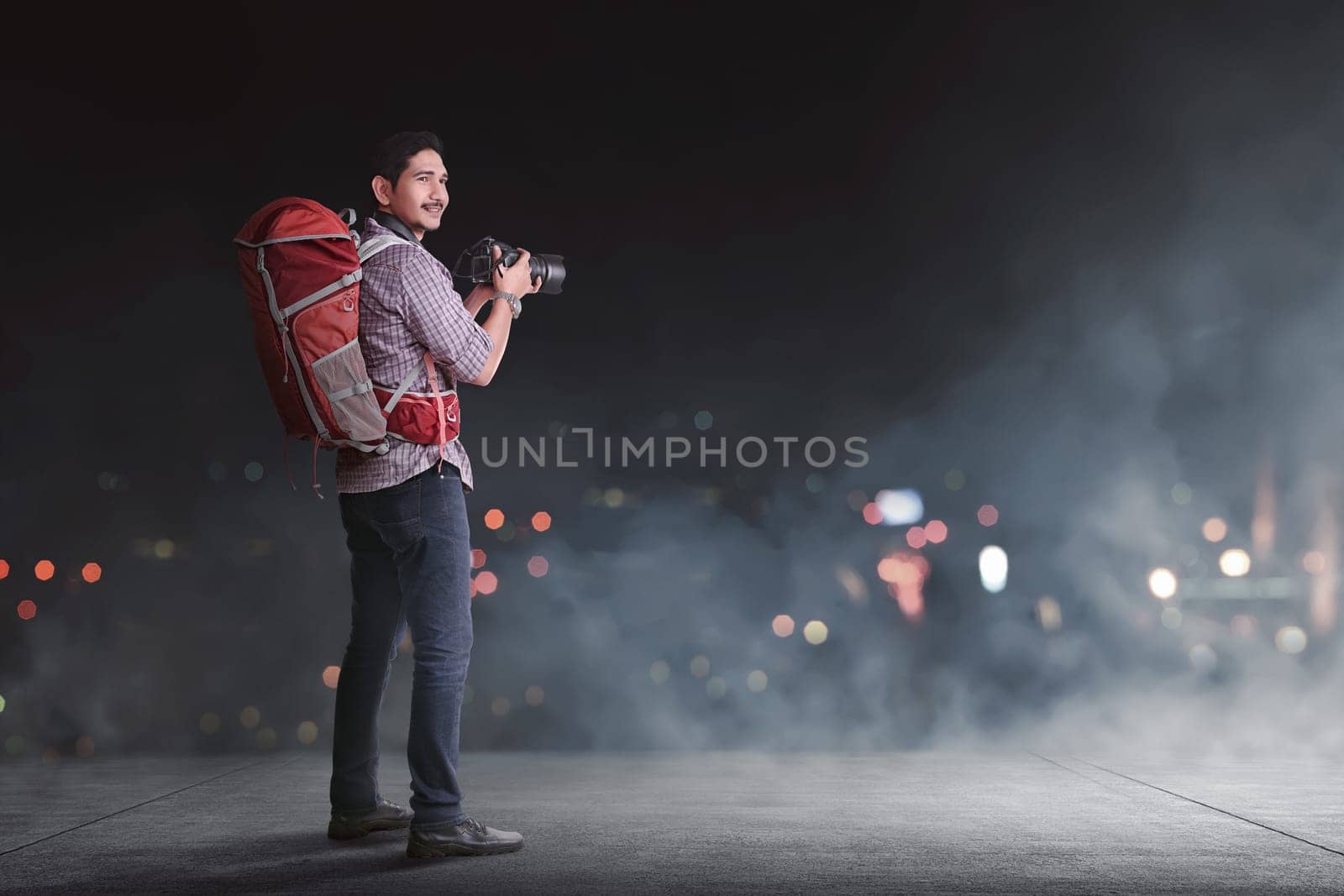 Handsome asian traveler with backpack and camera against blur light background