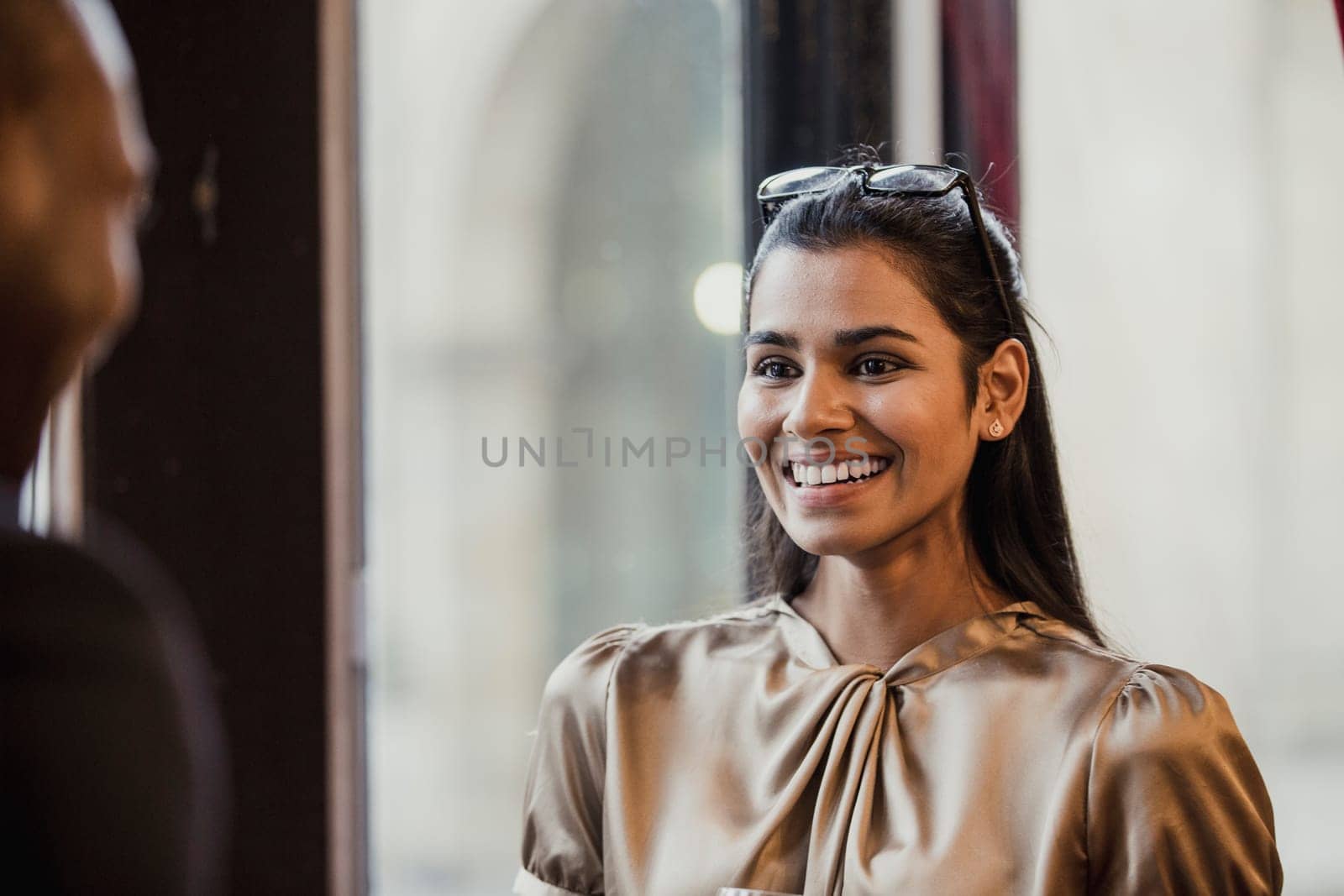 Over the shoulder view of a smiling businesswoman talking to an unrecognisable person.