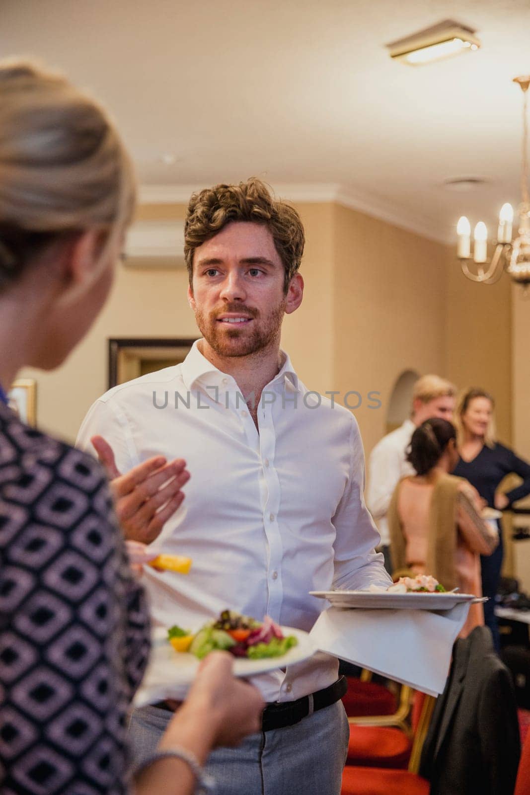 Rear view of a businesswoman talking to a businessman while on a lunch break from a conference meeting.