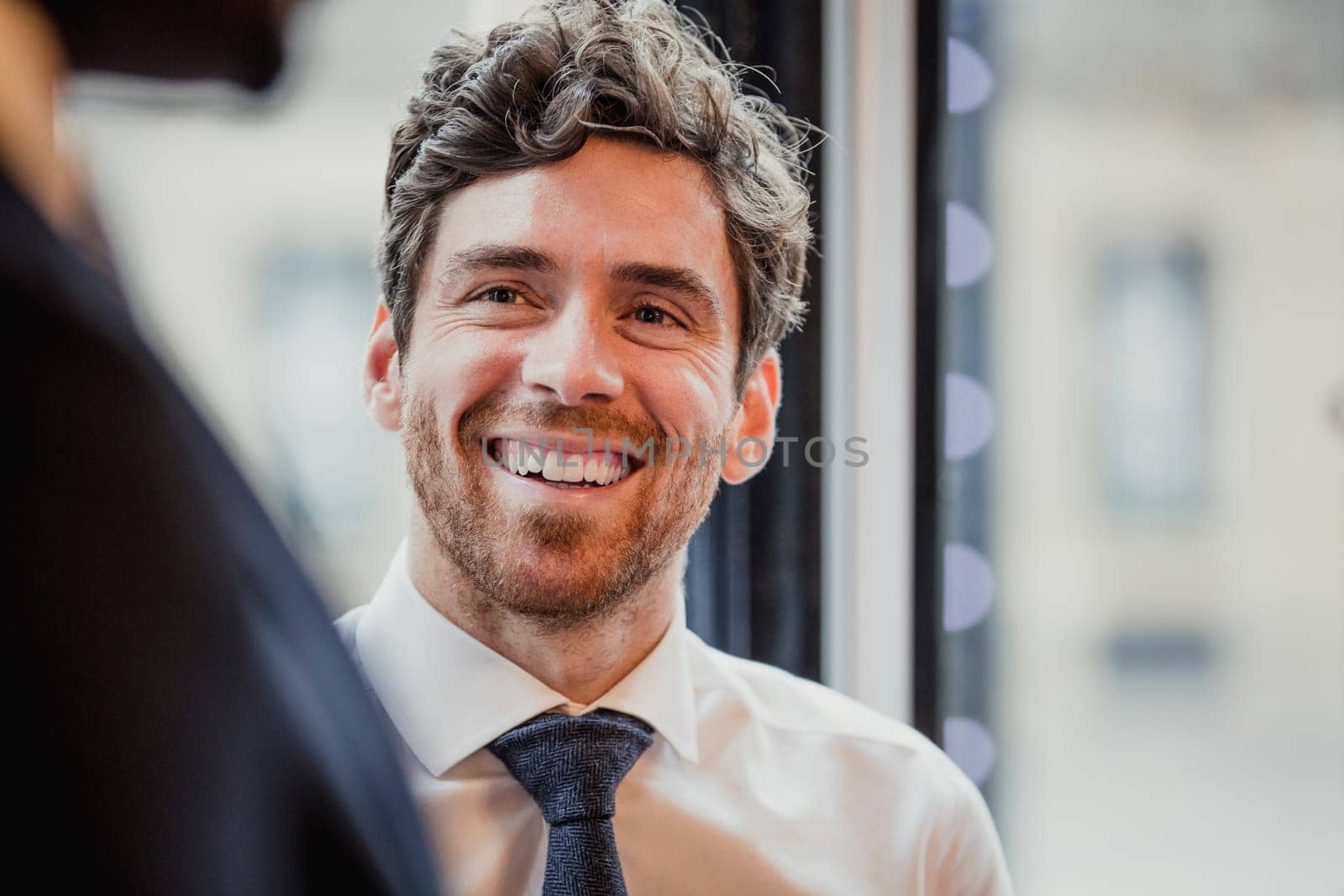 Close-up, over the shoulder view of a businessman looking and smiling at an unrecognisable person.