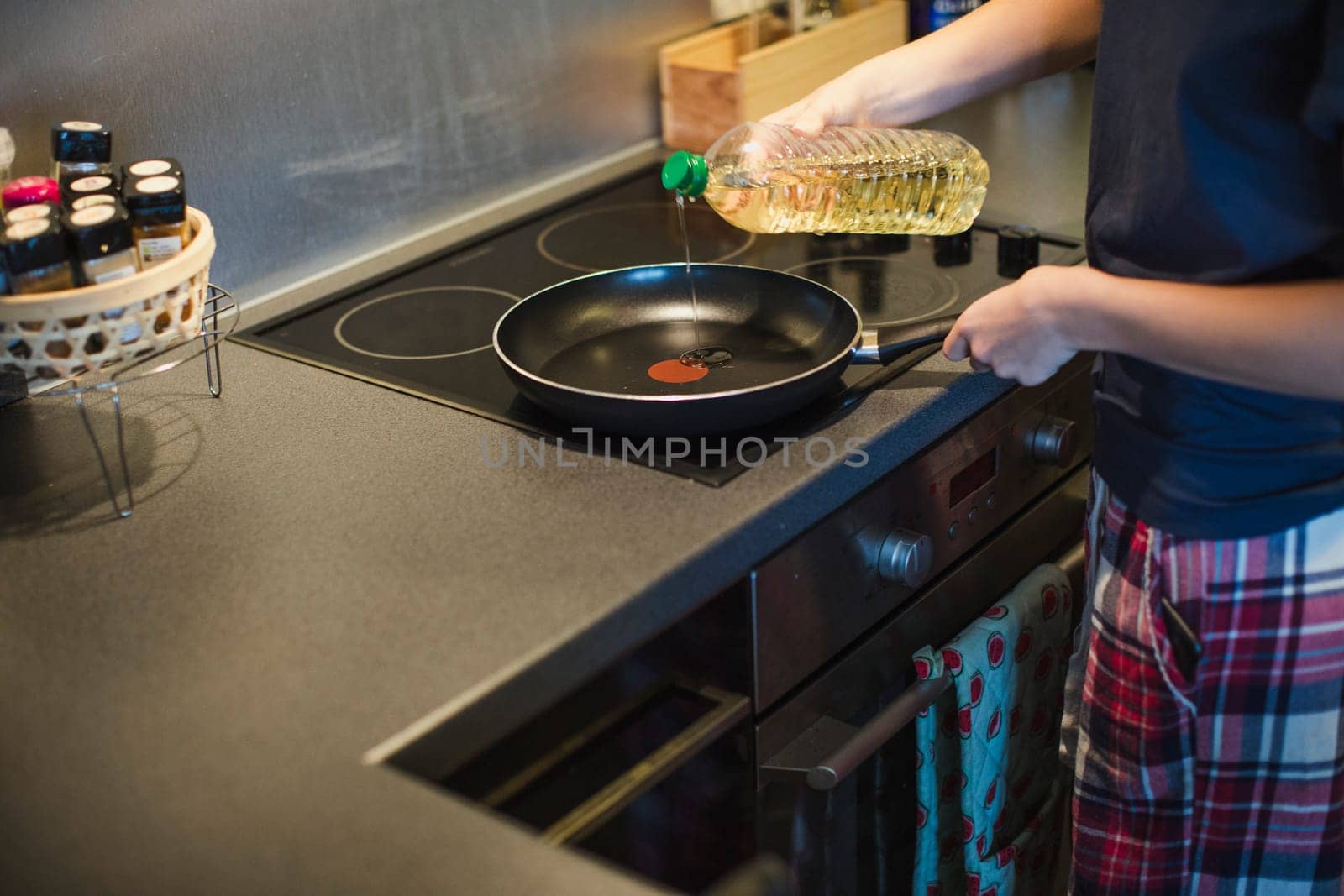 Unrecognisable person pouring oil into a frying pan to make some breakfast.