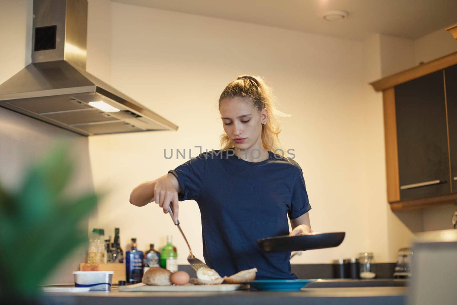 Front view of a young female adult makingan egg sandwich for her breakfast.