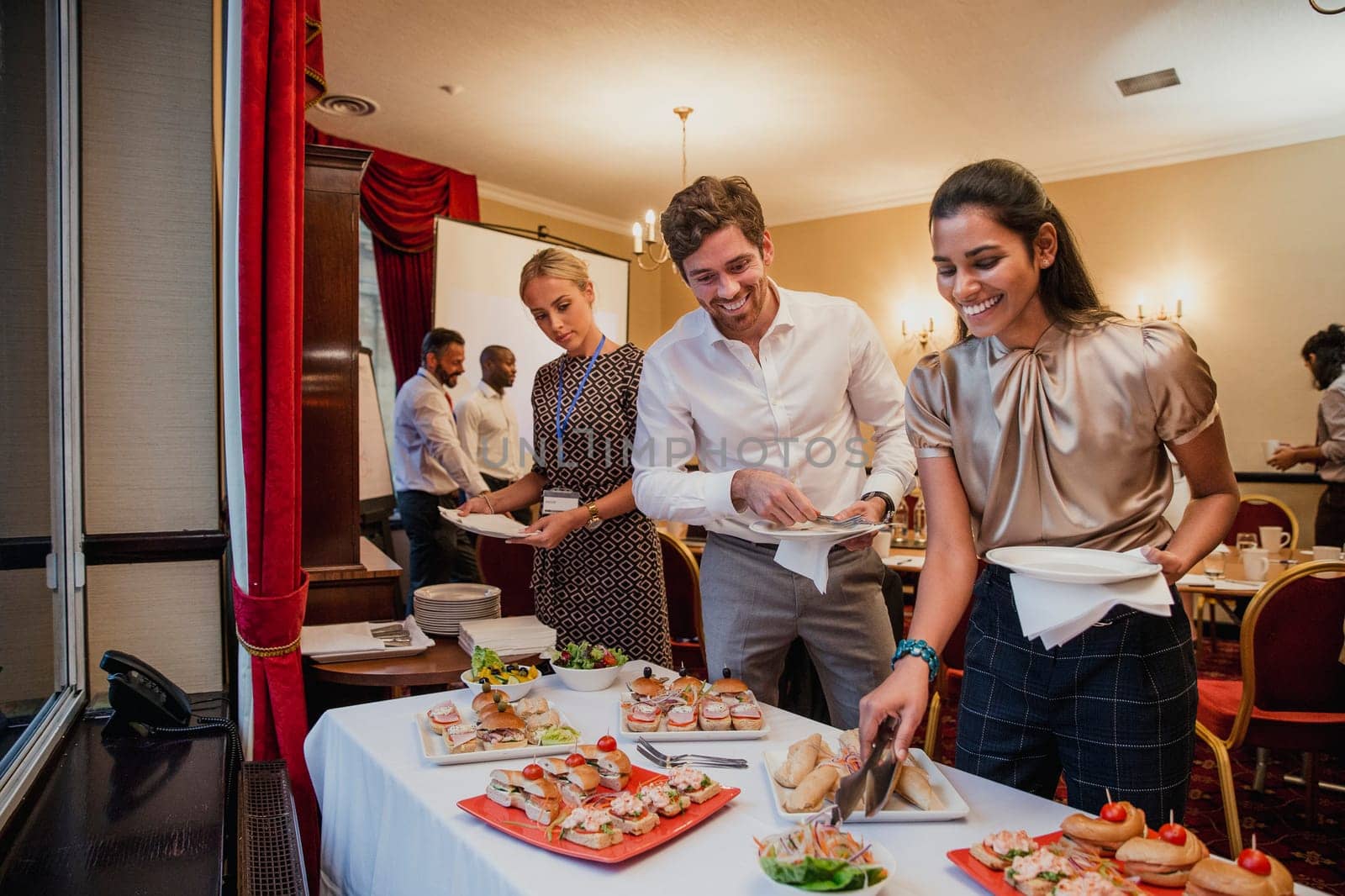 Front view of business people getting food from a buffet at a conference meeting.