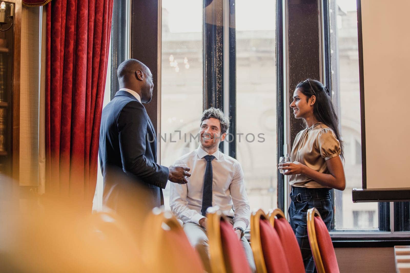 Side view of three business people, standing, talking after a business conference.