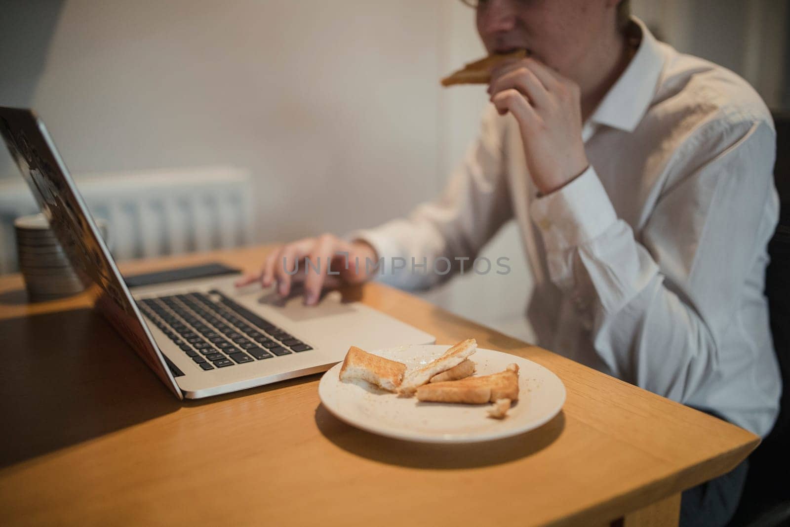 Young male adult checking emails while eating breakfast on a morning.