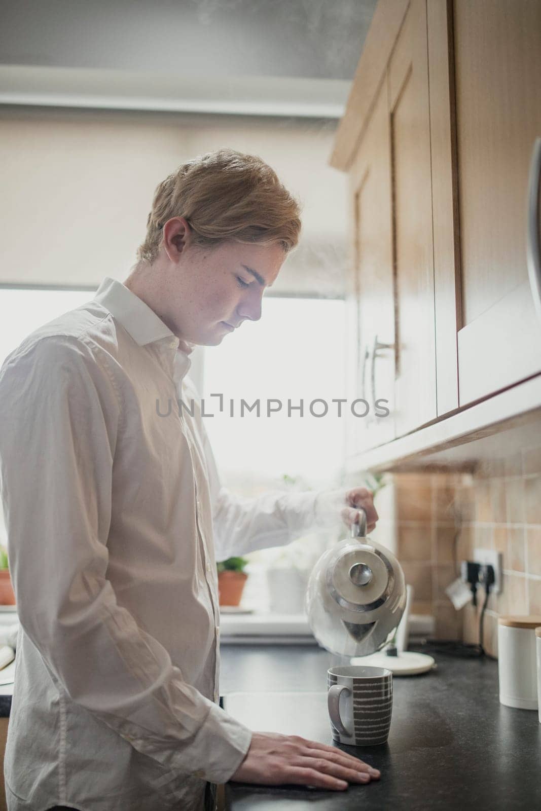 Young male adult making a cup of tea. Having regular cup of tea before work.