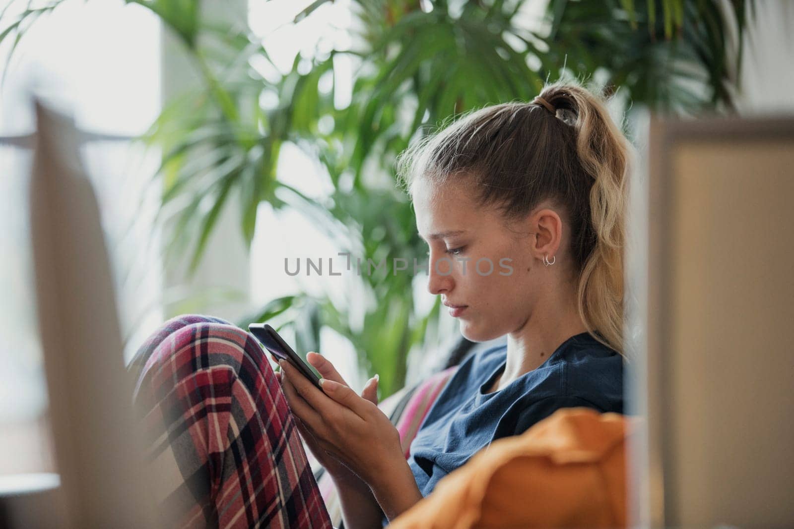 Side view of a young female adult sitting, relaxing, using her mobile phone.