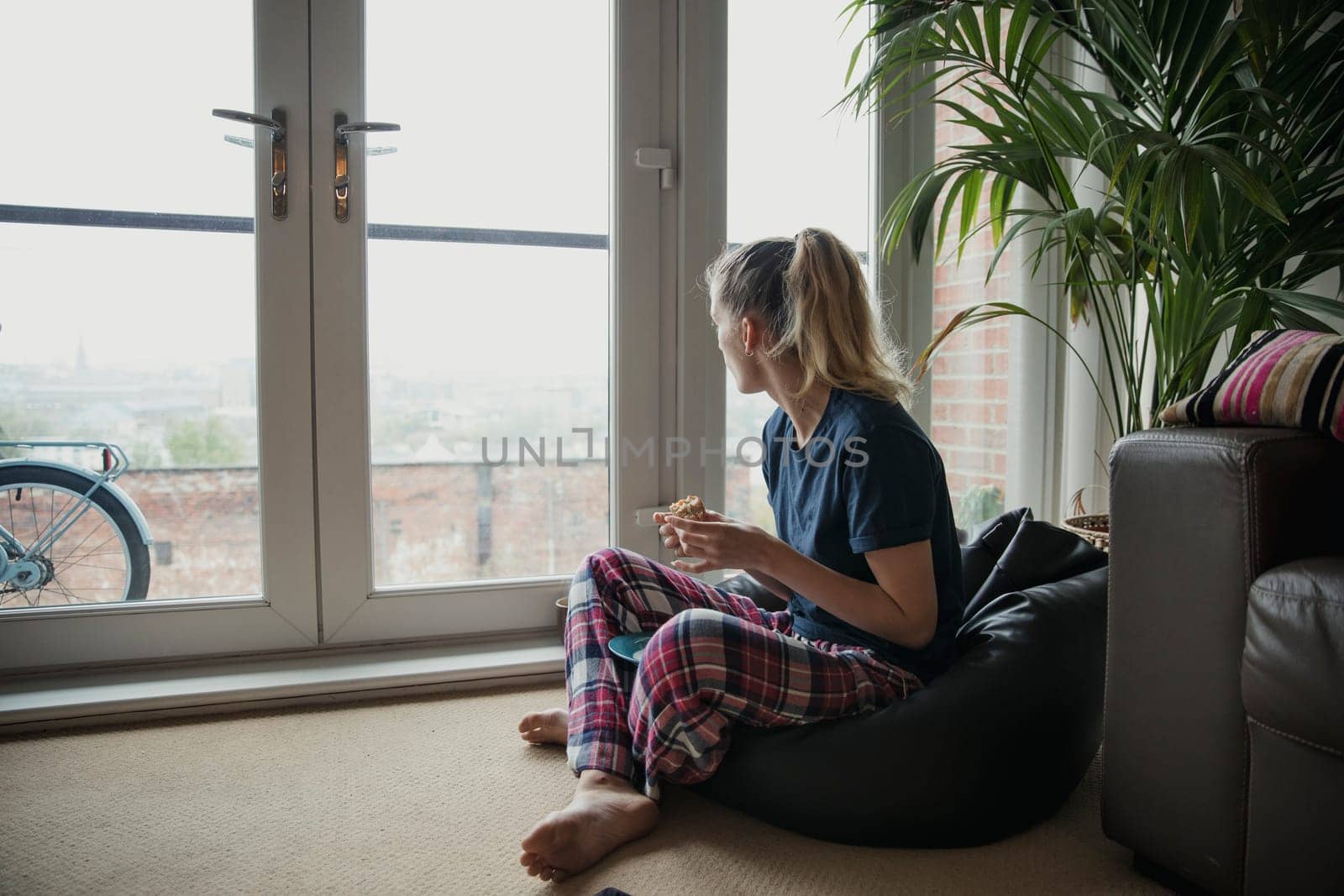 Young female adult enjoying her breakfast while looking out the window.