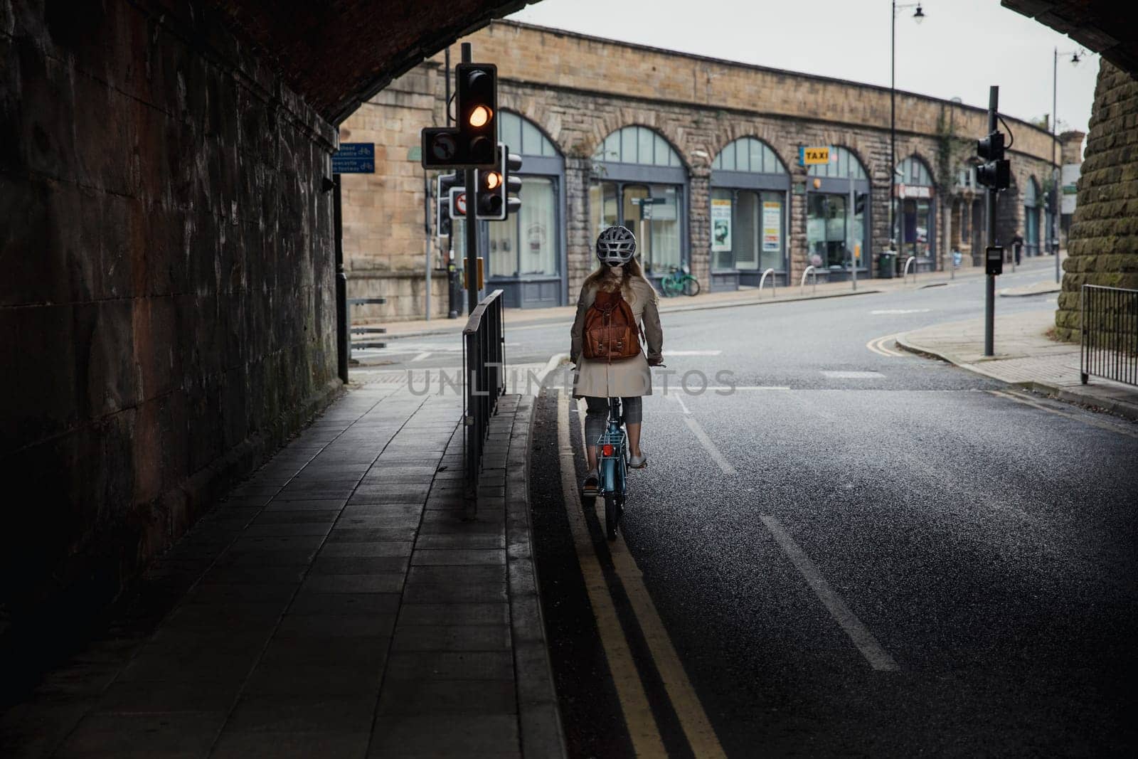 Rear view of a unrecognisable person cycling under a bridge to get to work.