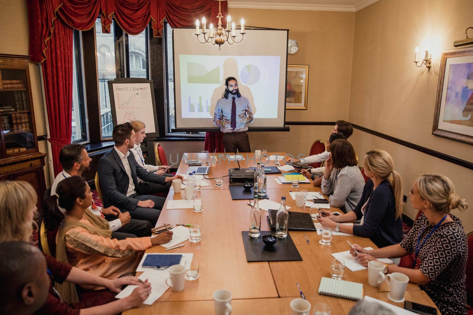 Businessman giving a presentation within a conference to a large group of business people.