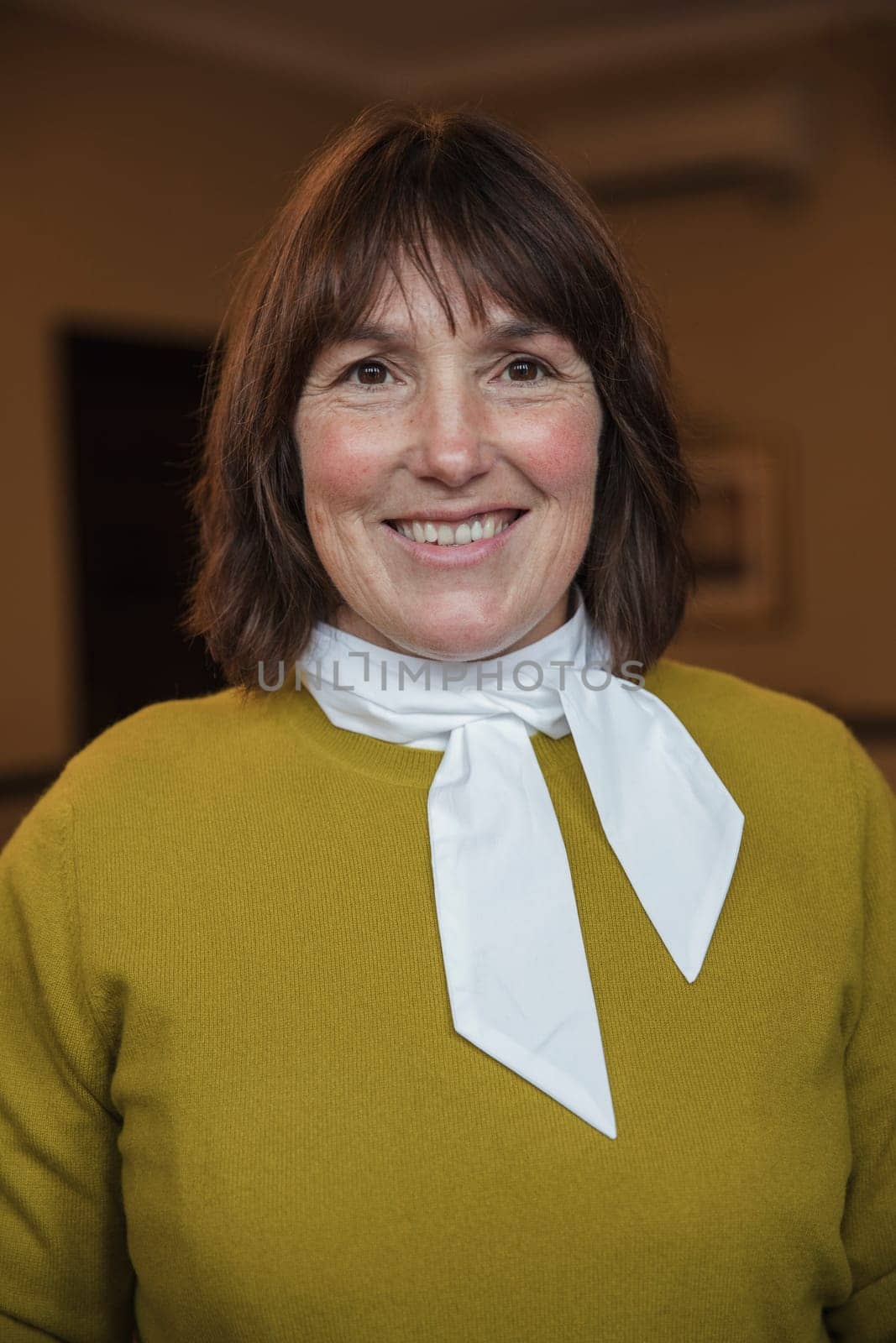 Close-up, front view portrait of a mature businesswoman smiling for the camera.