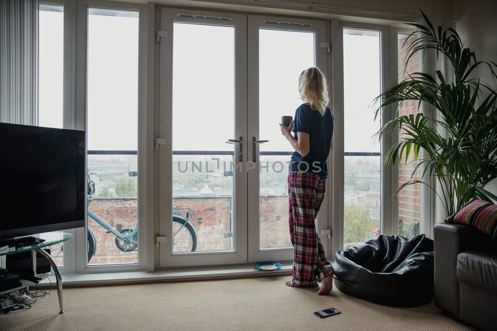 Rear view of a young female adult looking out the window after having her breakfast.