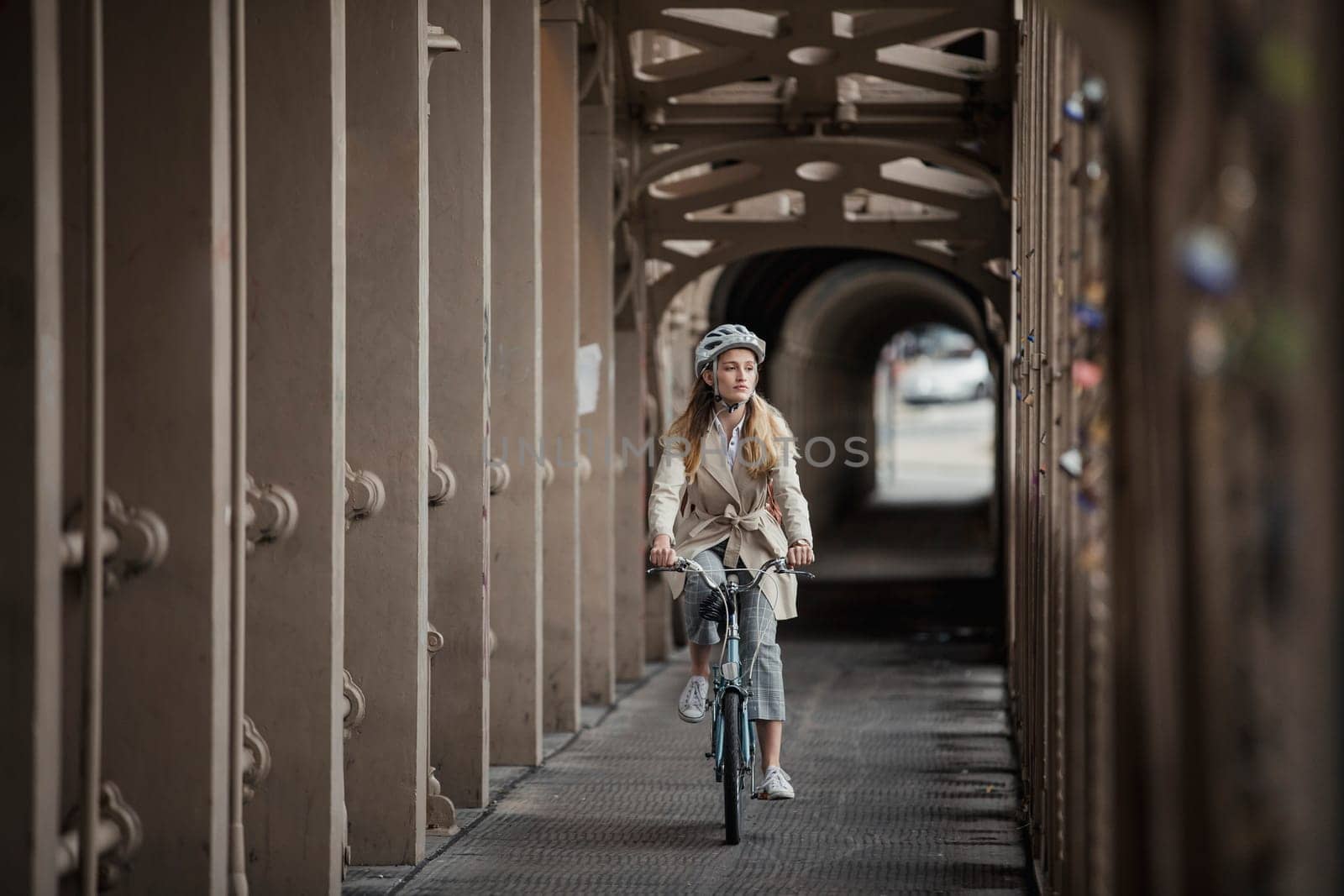 Wide angle, front view of a young female adult cycling over a bridge on the way to work.