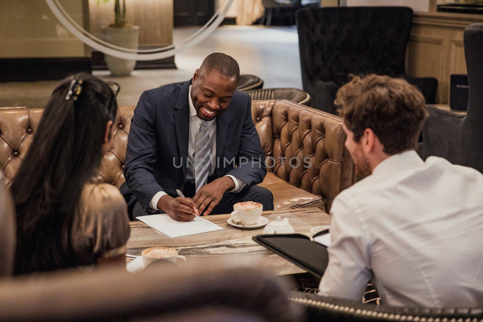 Rear view of three business people having a meeting in the reception of a building.