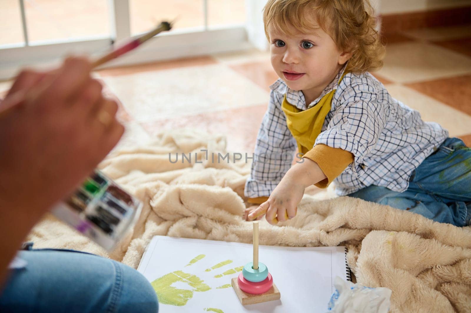 A joyful child engages in artistic activities at home, exploring creativity with paints and toys, depicting happiness and early learning in a nurturing family environment.