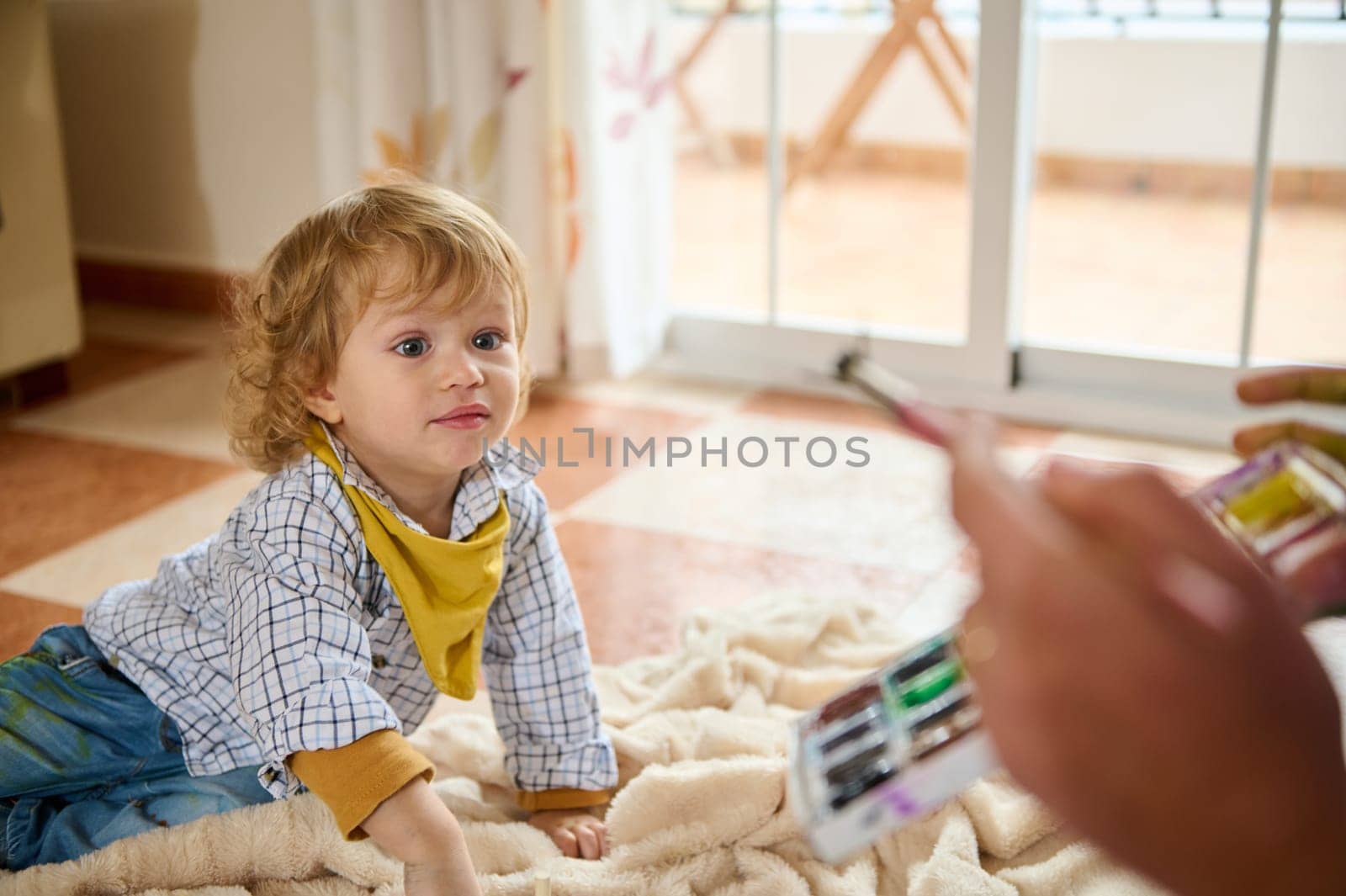 A young child enthusiastically interacts with an adult indoors, suggesting a playful and engaging family moment filled with joy.