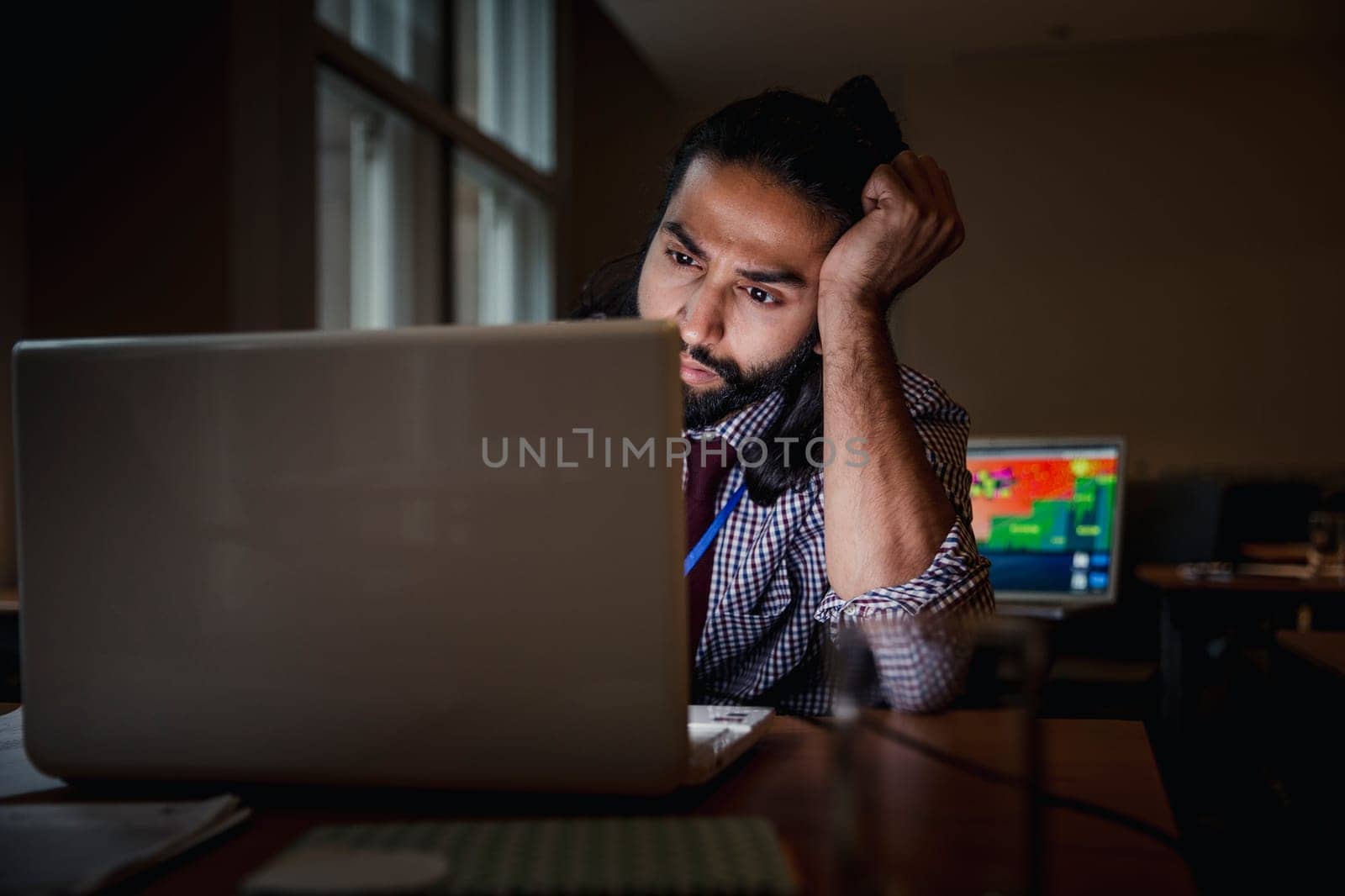 Mixed race young male adult working late at the office. Getting work finished off.