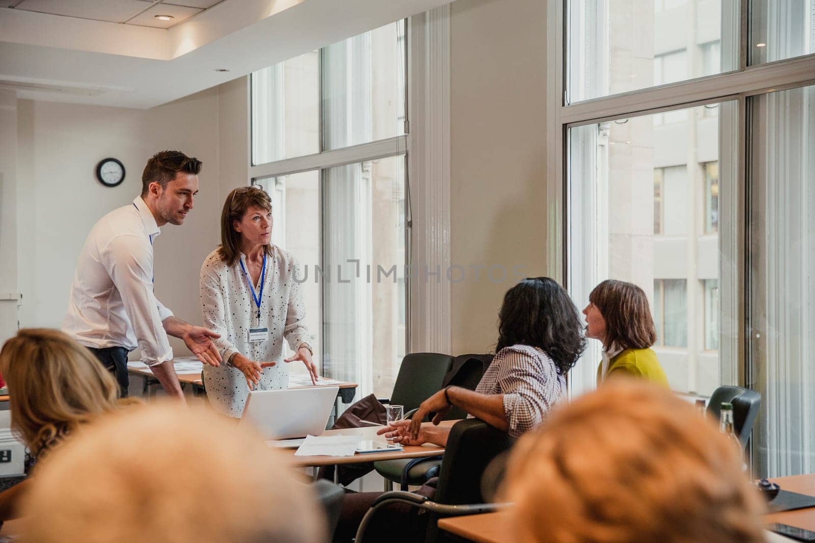 Businessman and woman talking to other their colleagues after giving a presentation within a meeting.