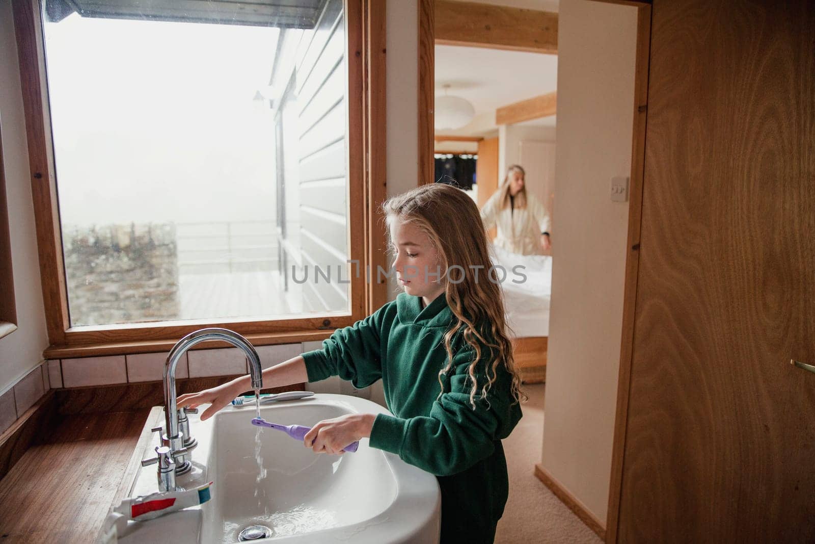 Little girl dressed in a school uniform brushing her teeth before going to school.