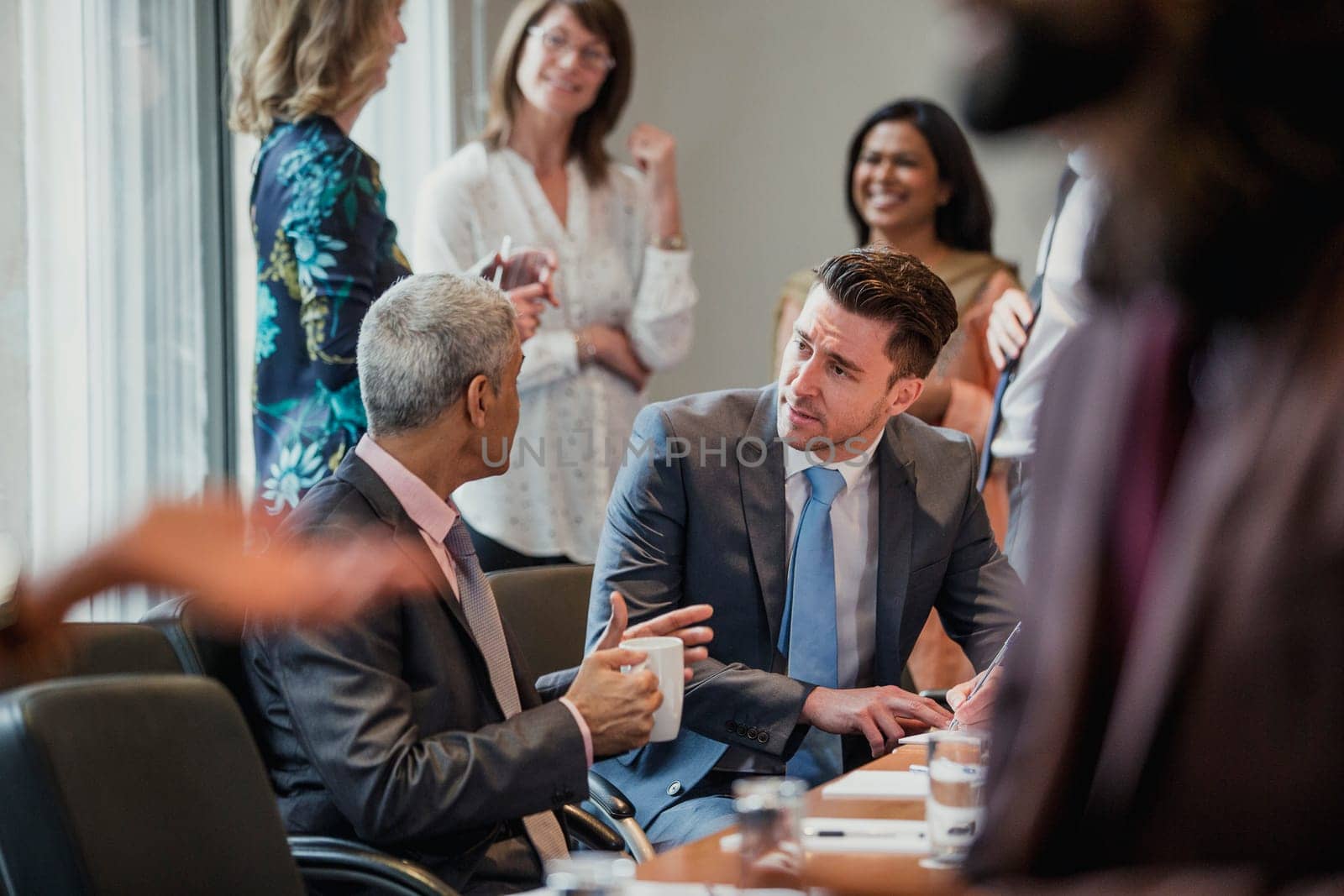 Two male businessmen talking during a conference. One businessman is making some notes.