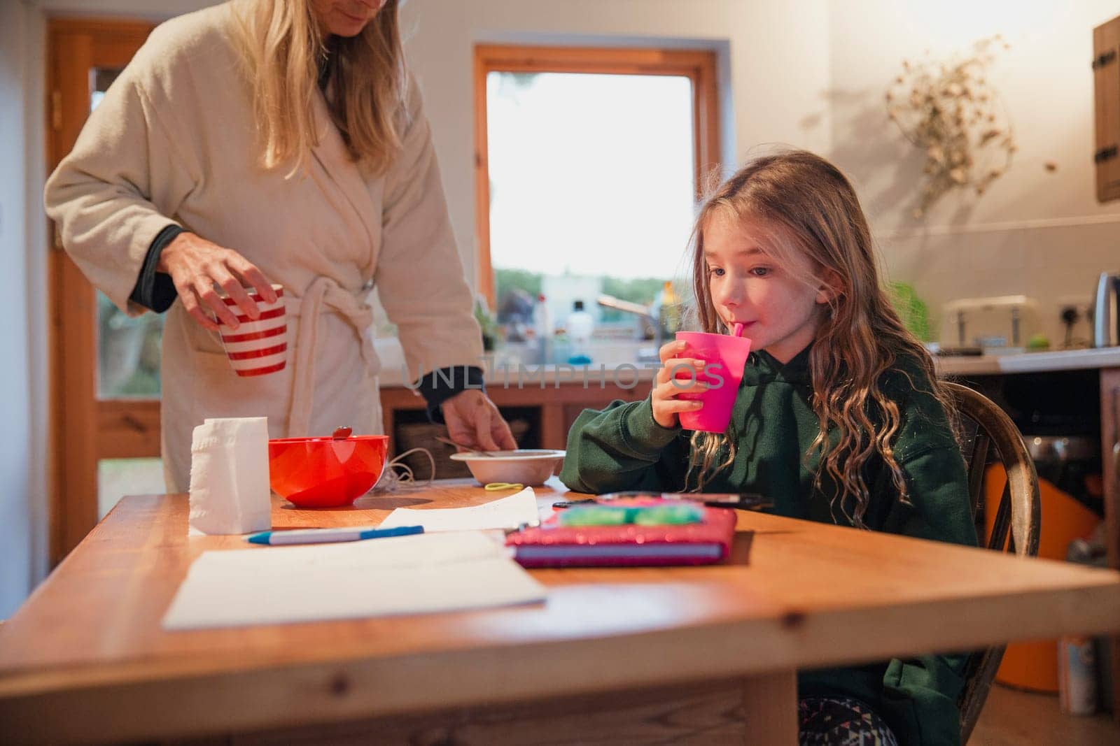 Mother cleaning up after her daughter has finished breakfast