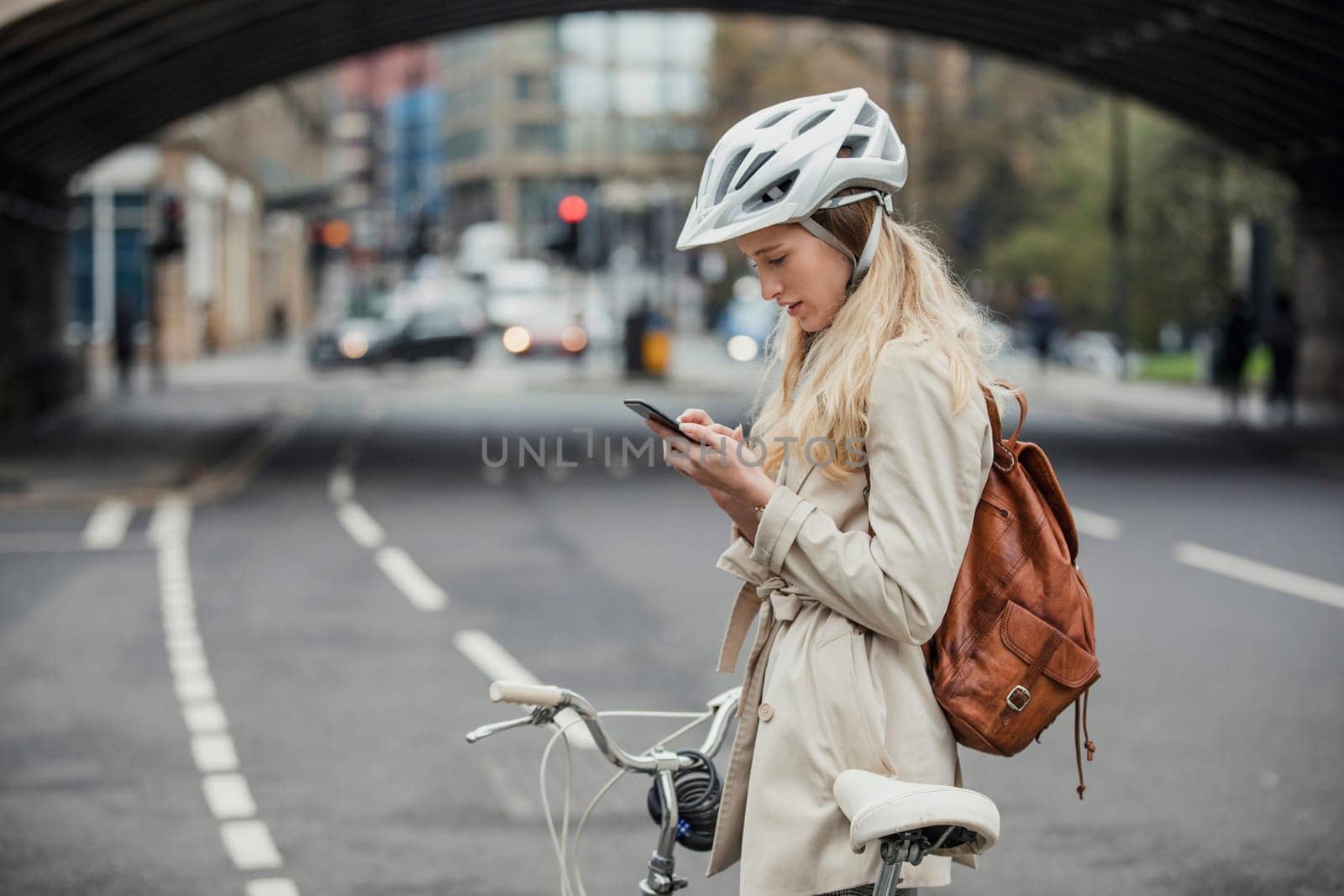 Young businesswoman checking the notifications on her mobile phone while cycling to work.