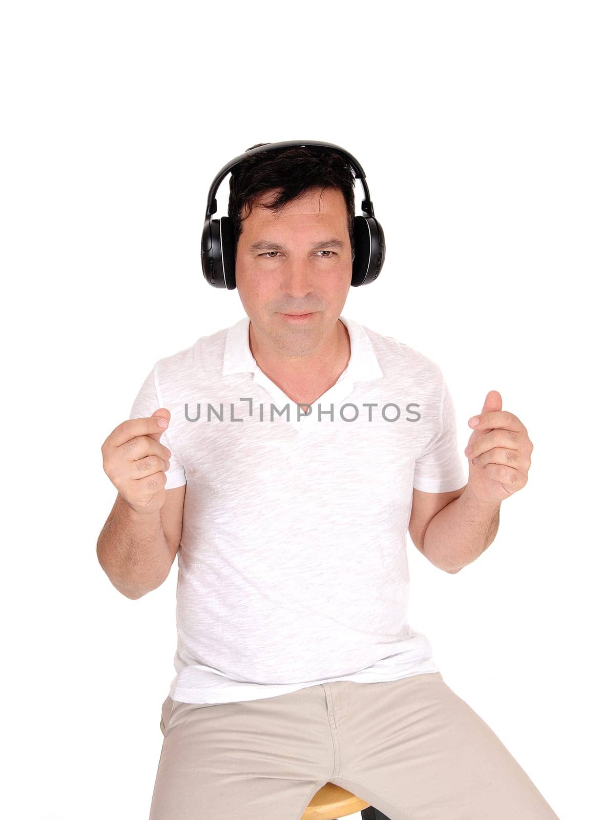 A good looking man sitting on a chair with his headphones on and.listening to music with is eyes closed, isolated for white background.