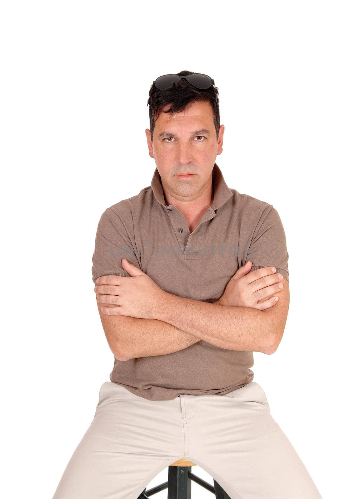 A handsome middle age man sitting on a chair with his arms closed.looking very serious, isolated for white background.