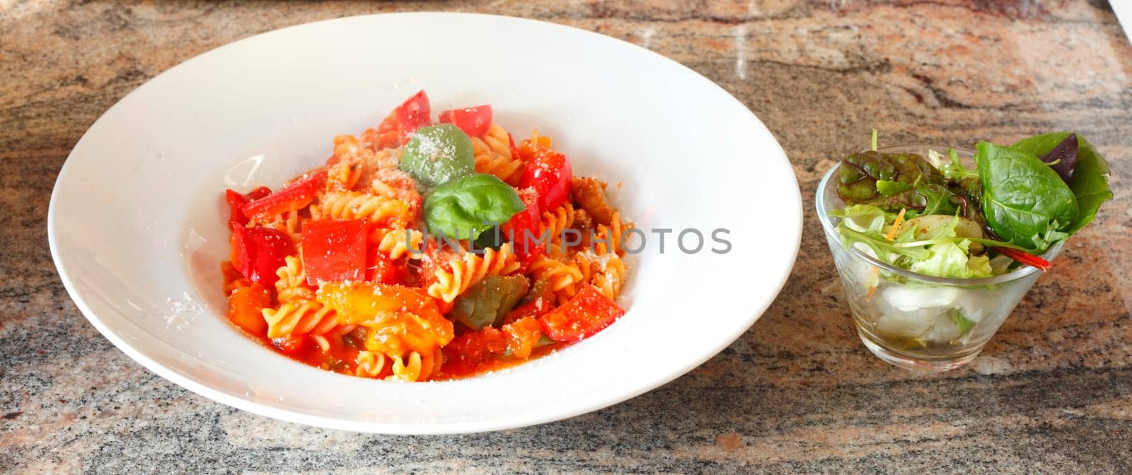 spiral pasta,fusilli,cooked with tomato sauce on a plate,Parmesan cheese and salad