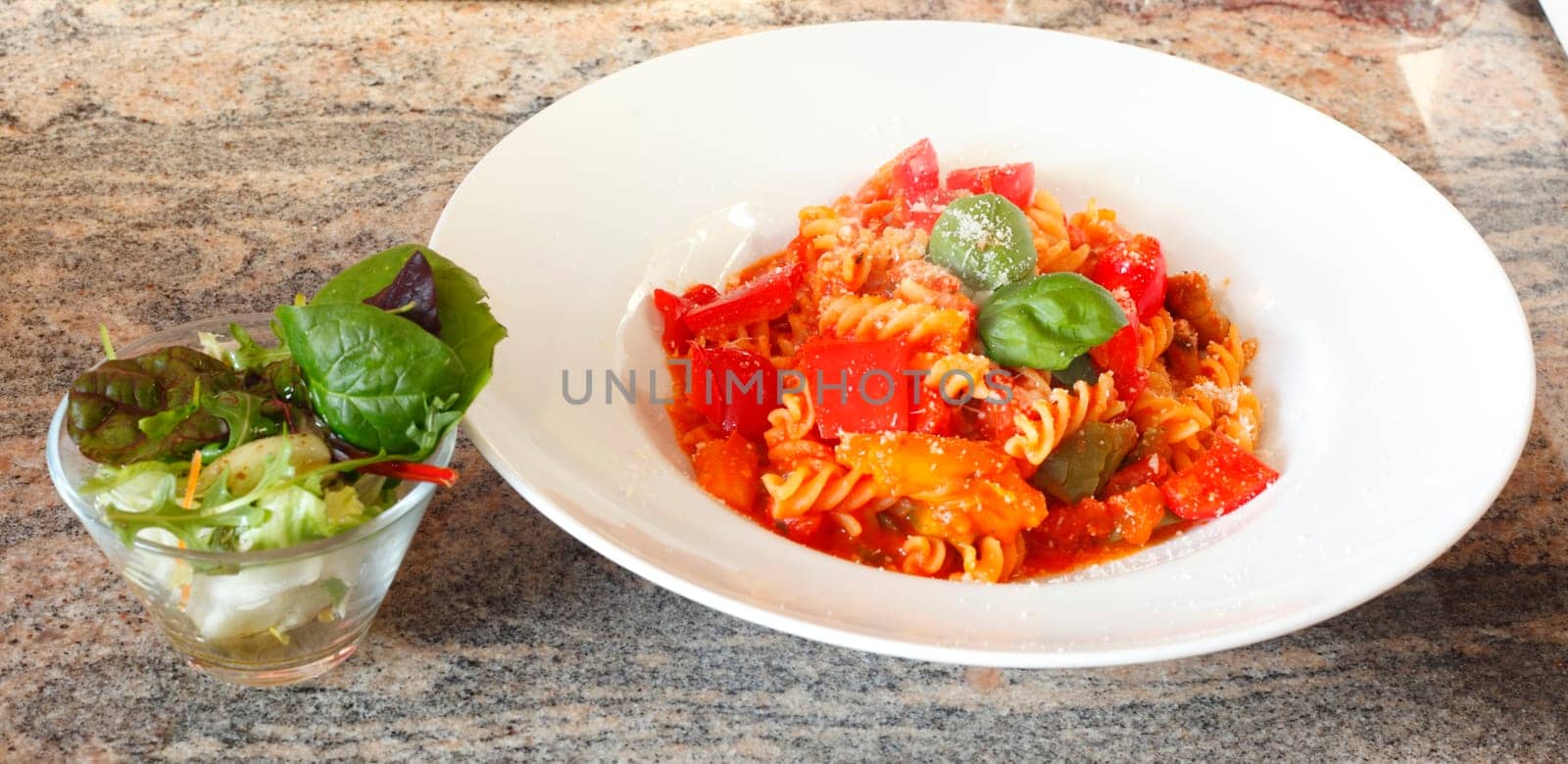 spiral pasta,fusilli,cooked with tomato sauce on a plate,Parmesan cheese and salad