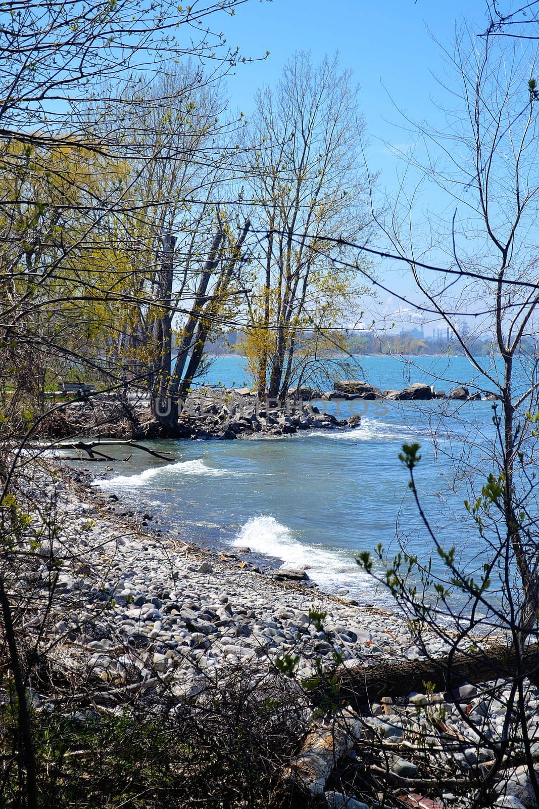 A closeup image of the shore of lake Ontario in the spring with blue sky.and small waves.