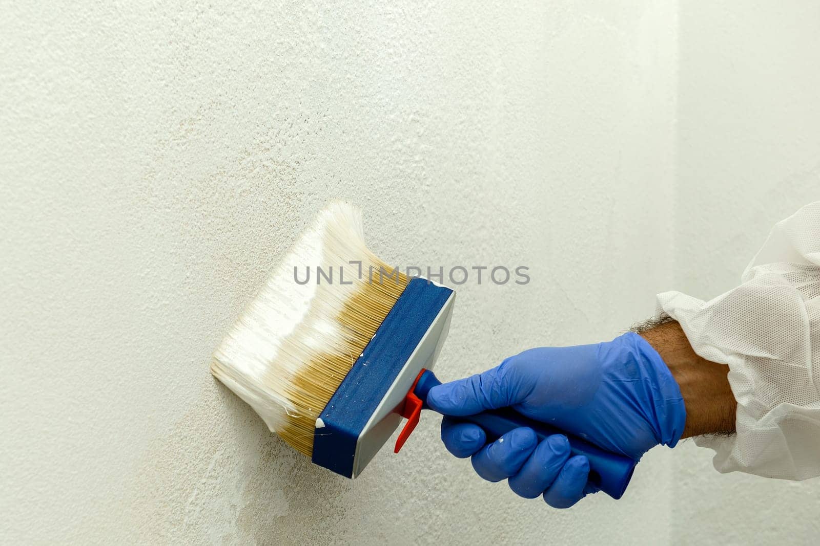 Painter paints the wall with the tint of white. Wall with serious moisture problems. Detail of the brush. white dye is prepared for the painter's job.