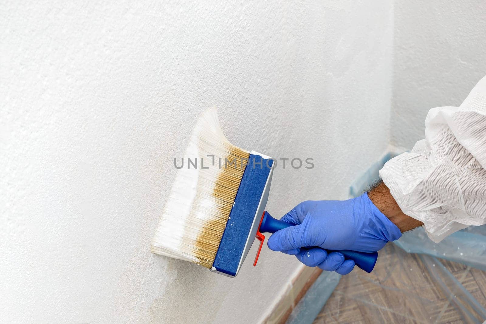 Painter paints the wall with the tint of white. Wall with serious moisture problems. Detail of the brush. white dye is prepared for the painter's job.
