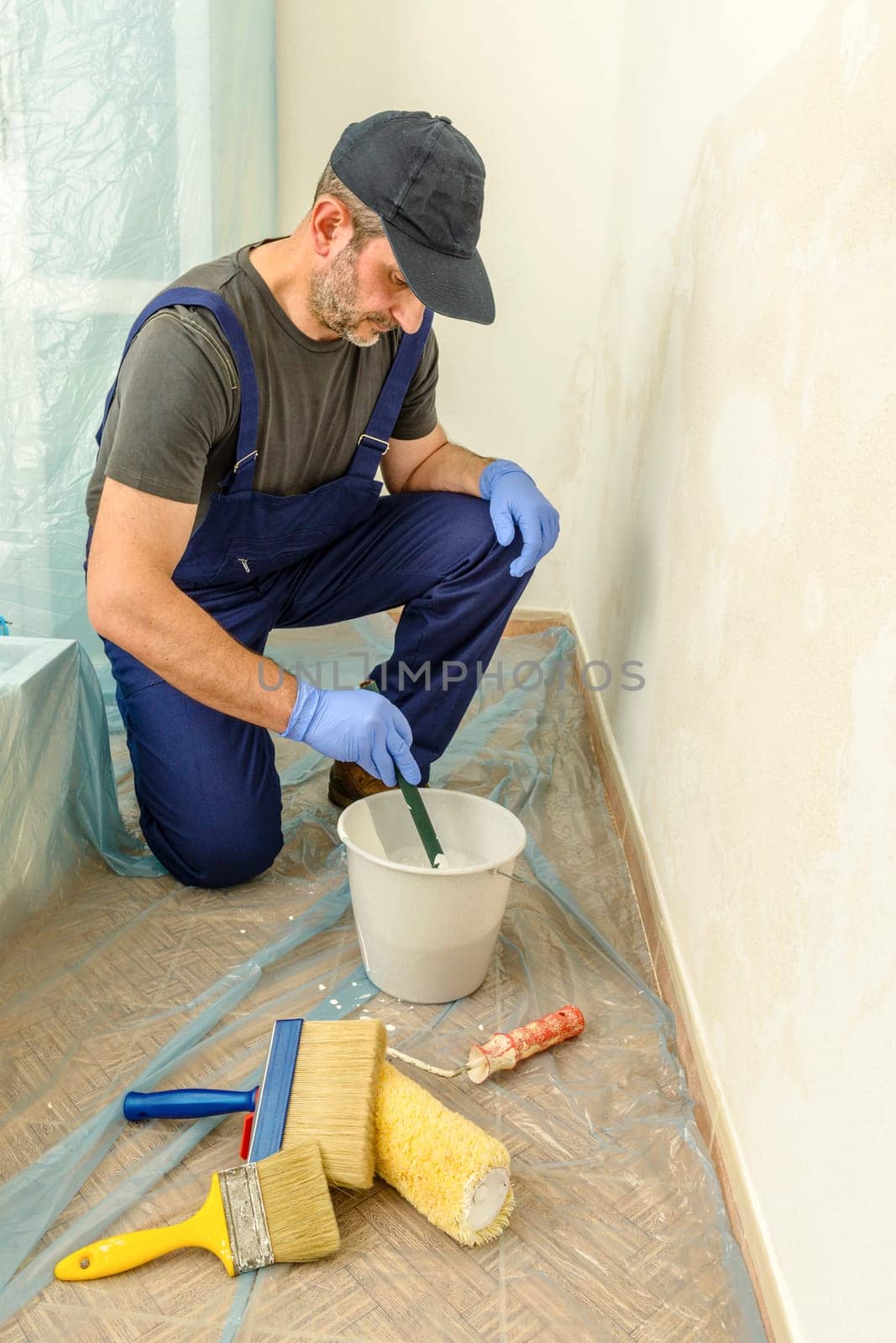 Painter paints the wall with the tint of white. Wall with serious moisture problems. Detail of the brush. white dye is prepared for the painter's job.
