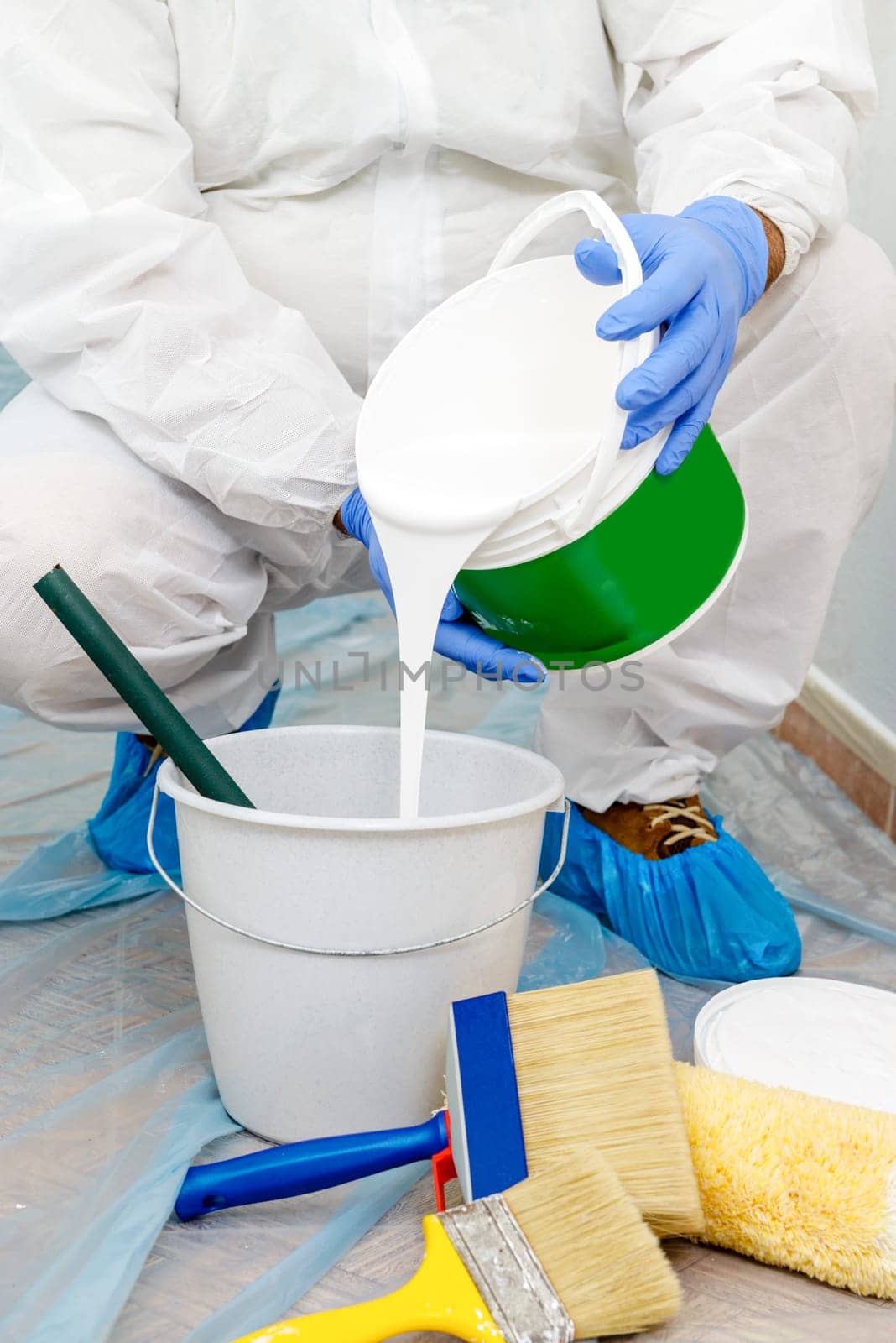 Painter paints the wall with the tint of white. Wall with serious moisture problems. Detail of the brush. white dye is prepared for the painter's job.
