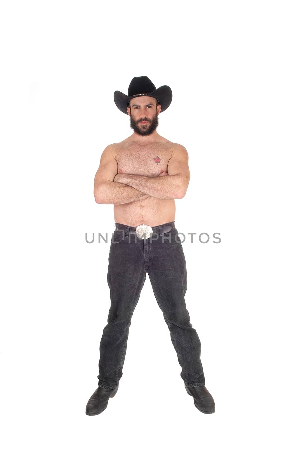 Young man standing shirtless, wearing a black cowboy hat and black.jeans with his arms crossed, isolated for white background.