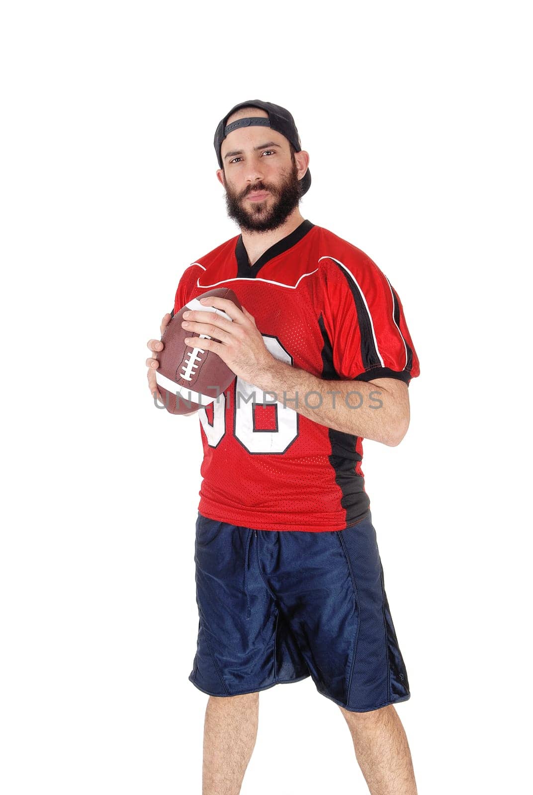 A football player in his red jersey and his brown football in his hand.standing, isolated for white background.
