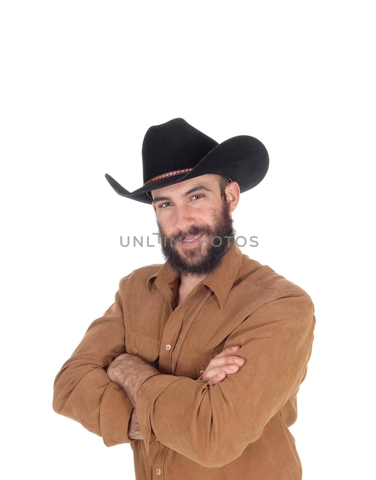 A happy handsome man in a brown shirt and black cowboy hat standing.with his arms crossed, isolated for white background.