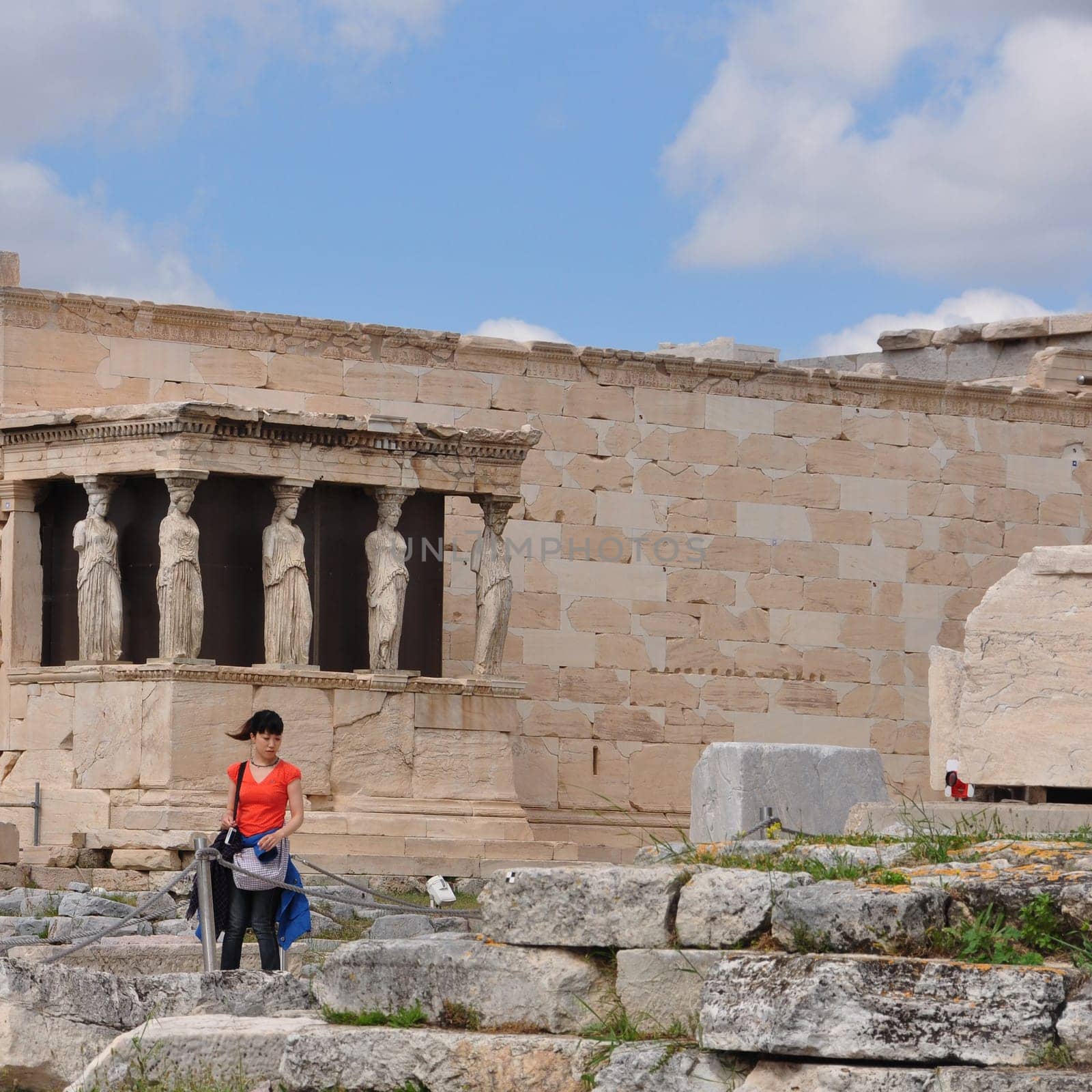 ATHENS, GREECE - MAY 6, 2014: Woman in front of the Porch of Caryatids. Erechtheion ancient temple ruins at the Acropolis of Athens, Greece.