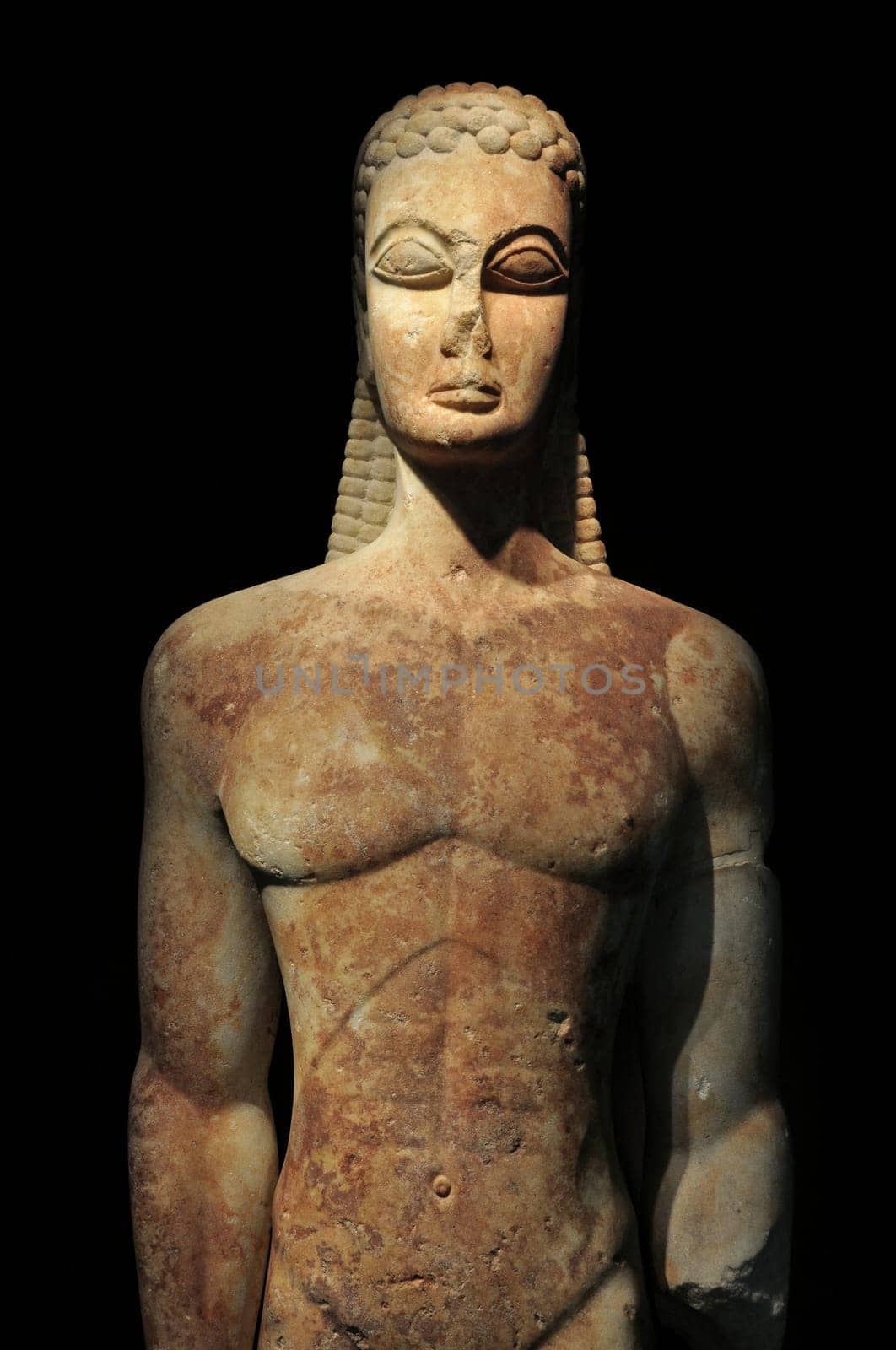 Kouros of the sacred gate ancient greek statue of male figure on black background. Kerameikos museum, Athens Greece.