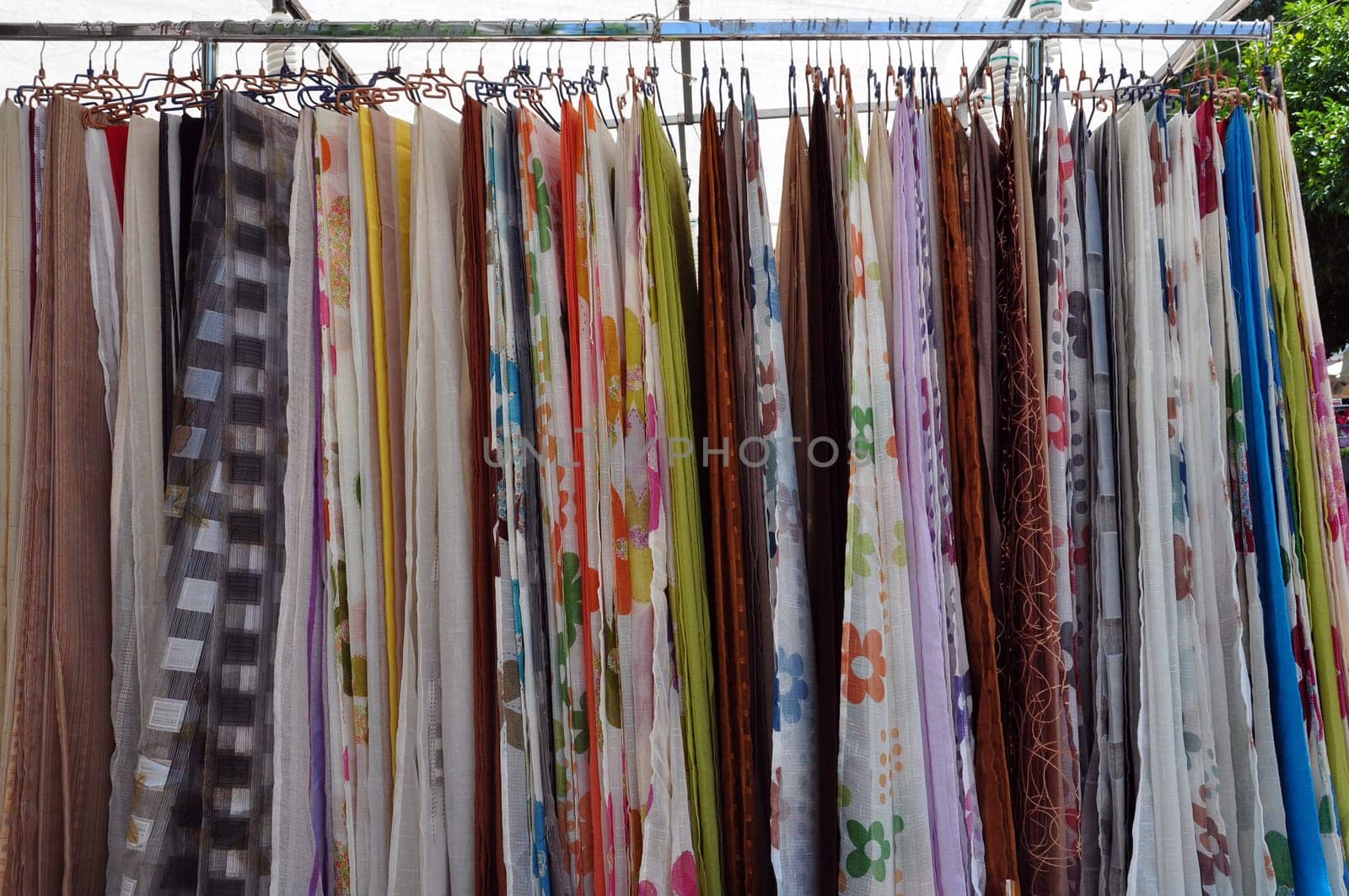 Colorful drapes for sale at street market. Abstract textile fabric background.