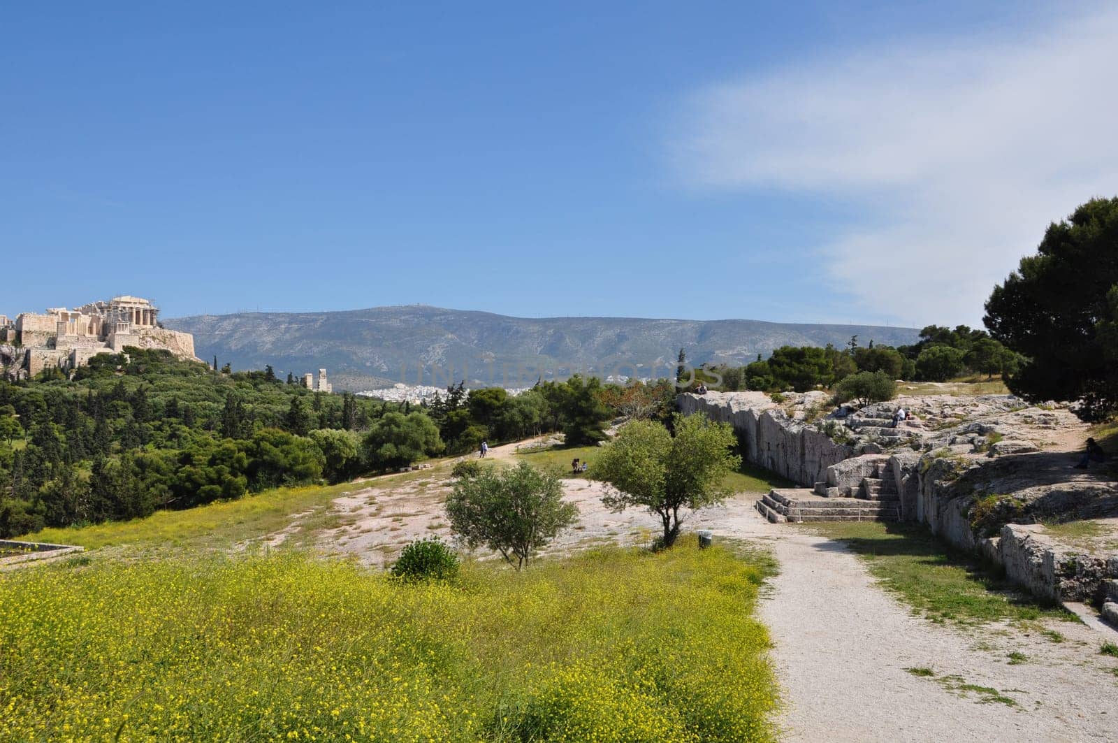 ATHENS, GREECE - APRIL 20, 2014: Pnyx monument speaker's platform and rock carved steps ancient democratic assembly of Athenian citizens with view to the Acropolis. Athens in springtime.