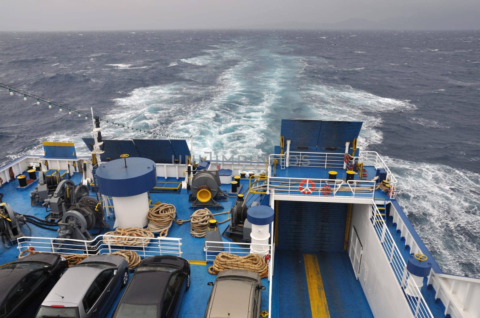 Ferry boat at sea. Cars and equipment on ship deck.