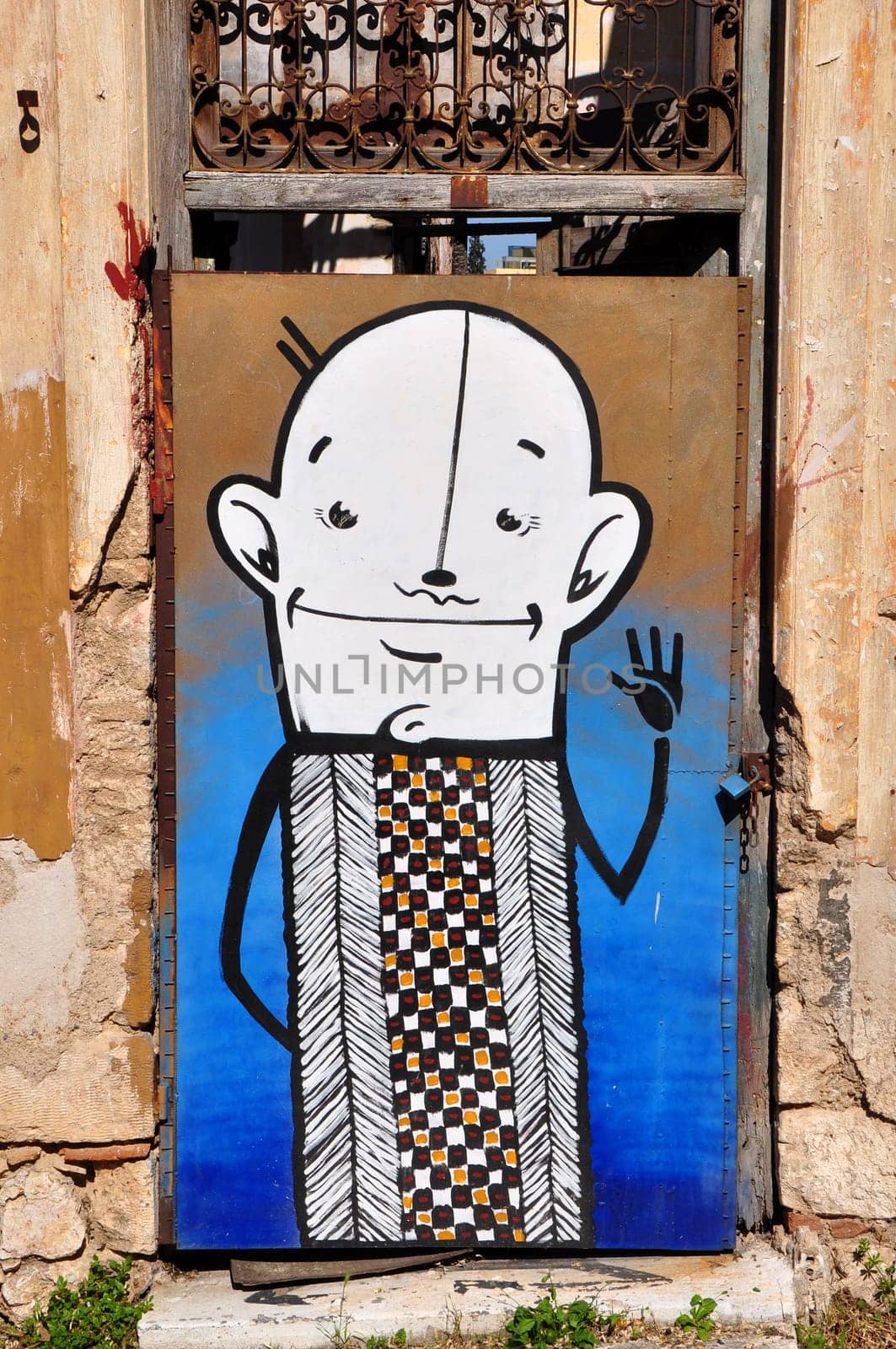 ATHENS, GREECE - APRIL 15, 2014: Funny cartoon character abstract graffiti on the boarded up door of an abandoned house.