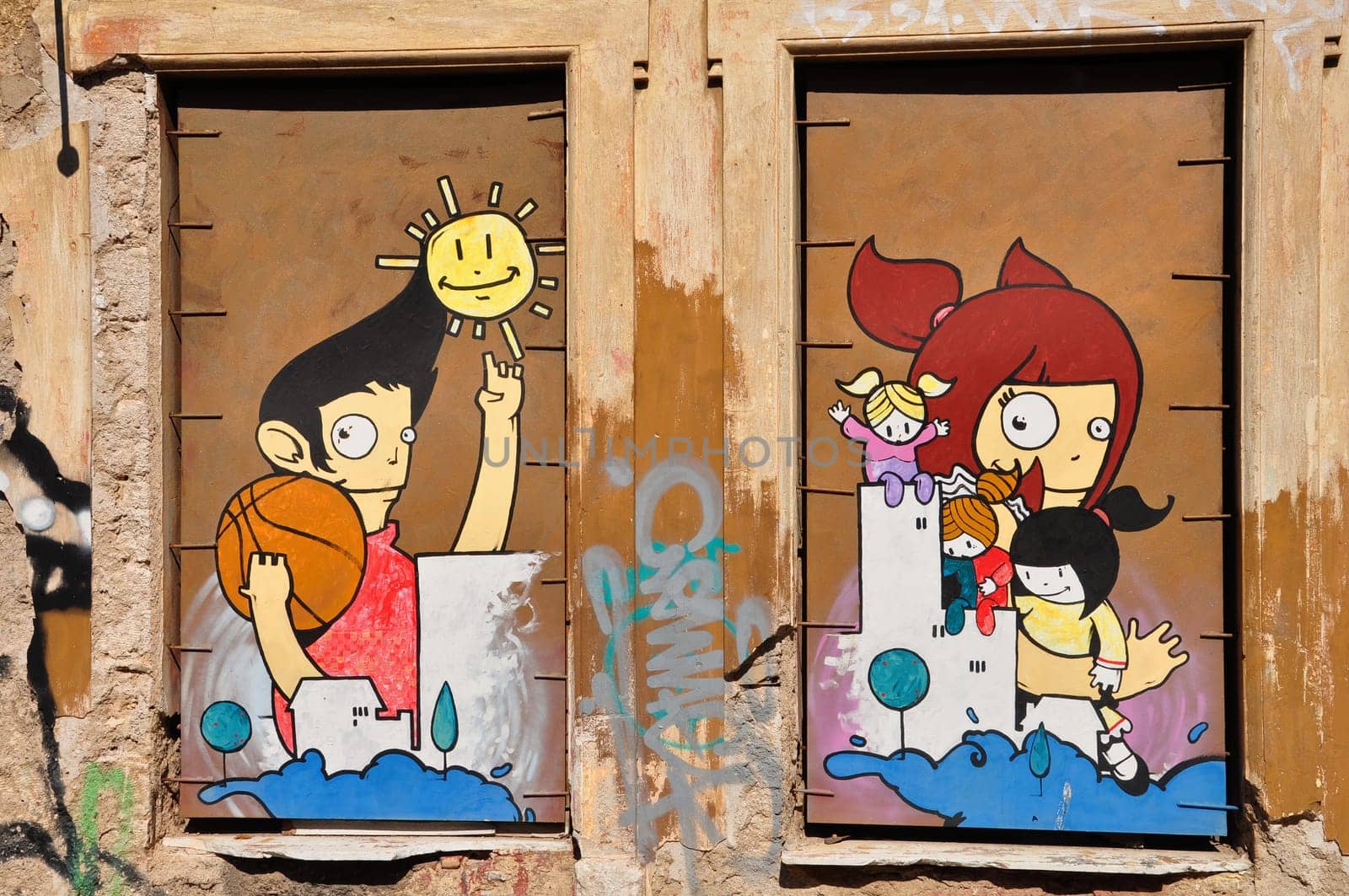 ATHENS, GREECE - APRIL 15, 2014: Colorful graffiti artwork happy cartoon figures on boarded up windows. Youth culture urban street art.