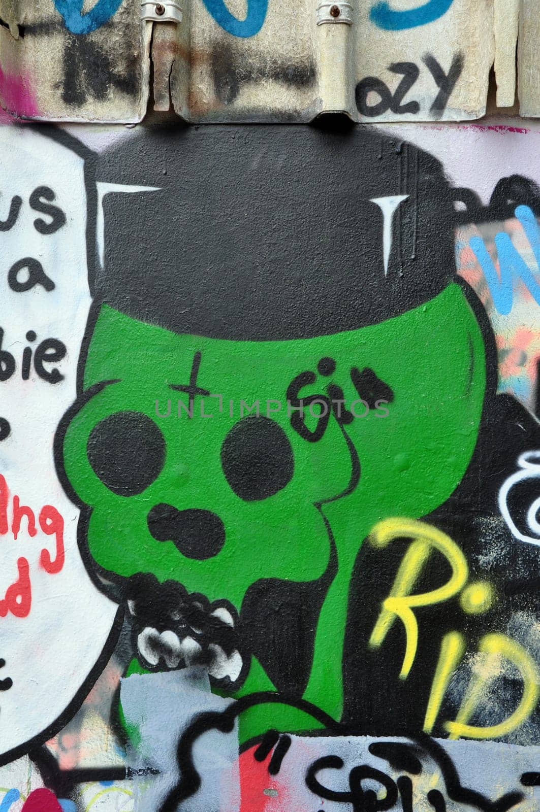 ATHENS, GREECE - JULY 25, 2014: Green skull spray painted on a wall covered with graffiti and tags. Urban street art.